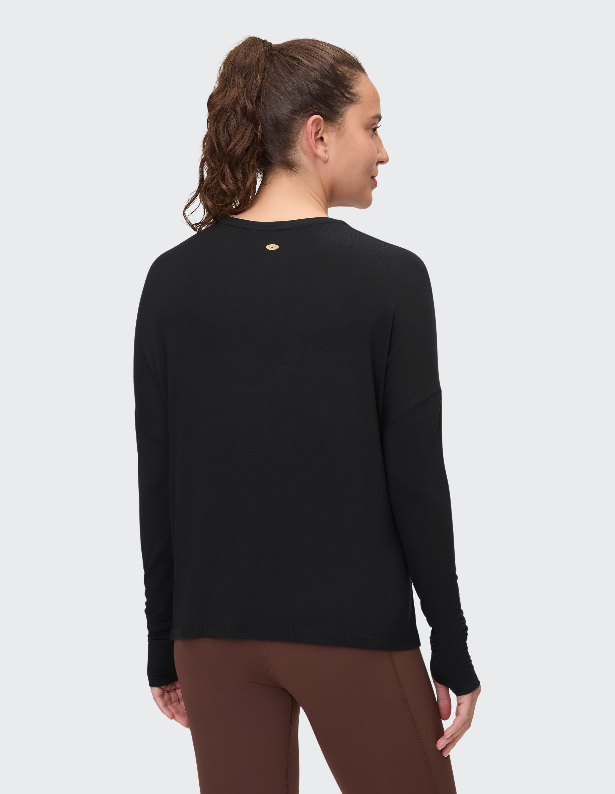 Rückansicht einer Frau in einem schwarzen Langarmshirt, gepaart mit braunen Leggings.