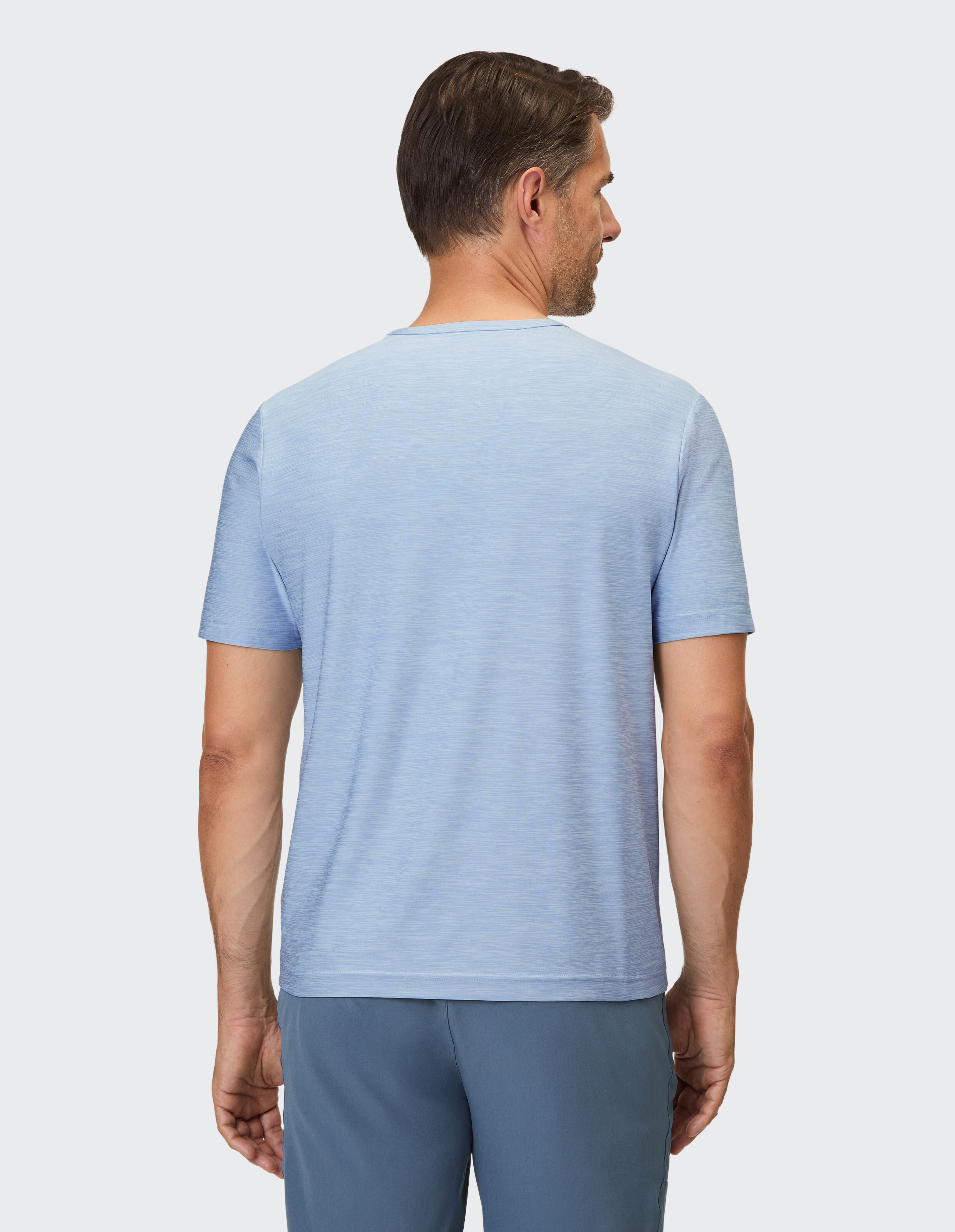 Ein Mann im Profil trägt ein hellblaues T-Shirt mit kurzärmeligem Rundhalsausschnitt und feiner Textur.