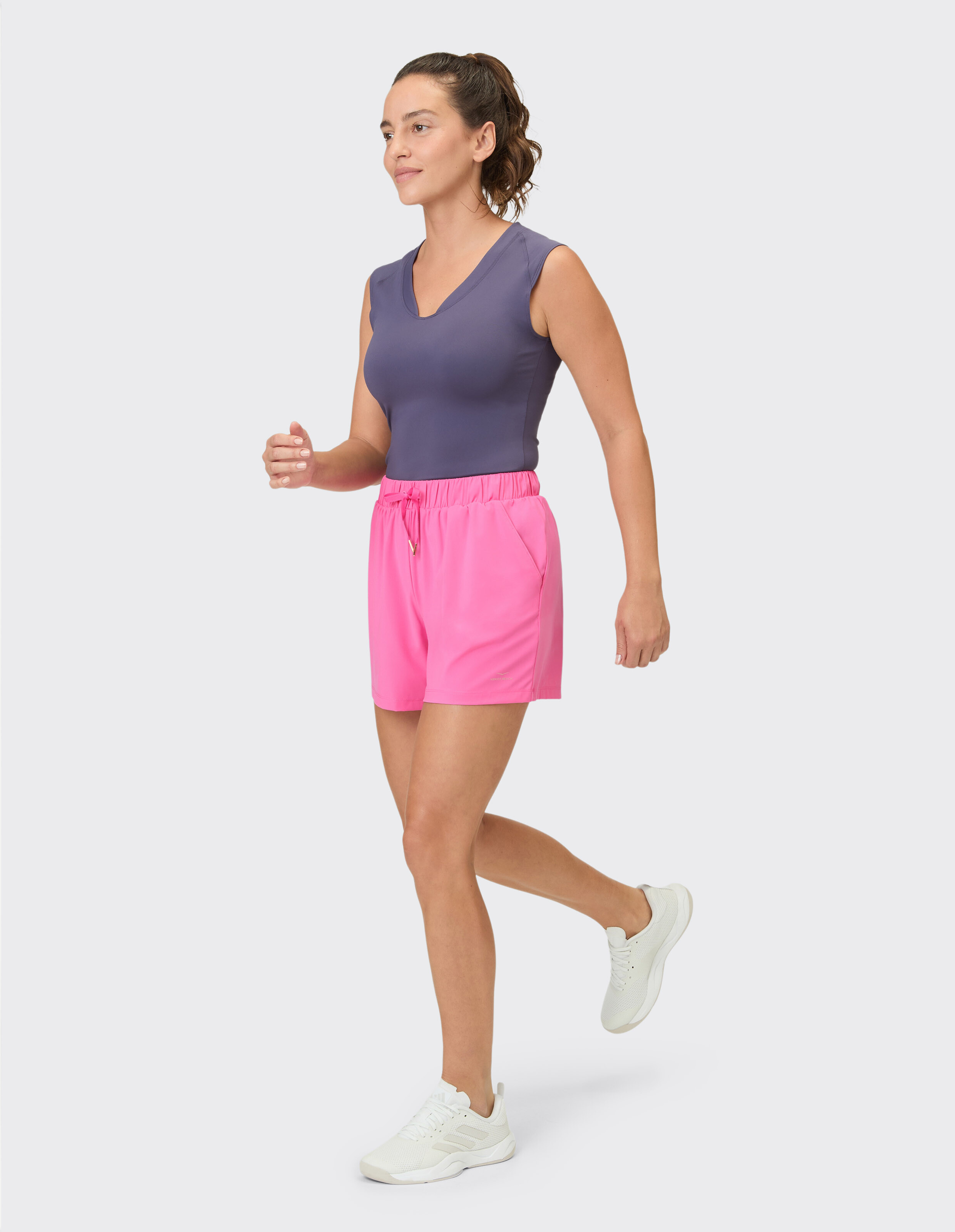 Frau trägt ein lila ärmelloses Top und rosa Freizeitshorts für einen aktiven Lebensstil.