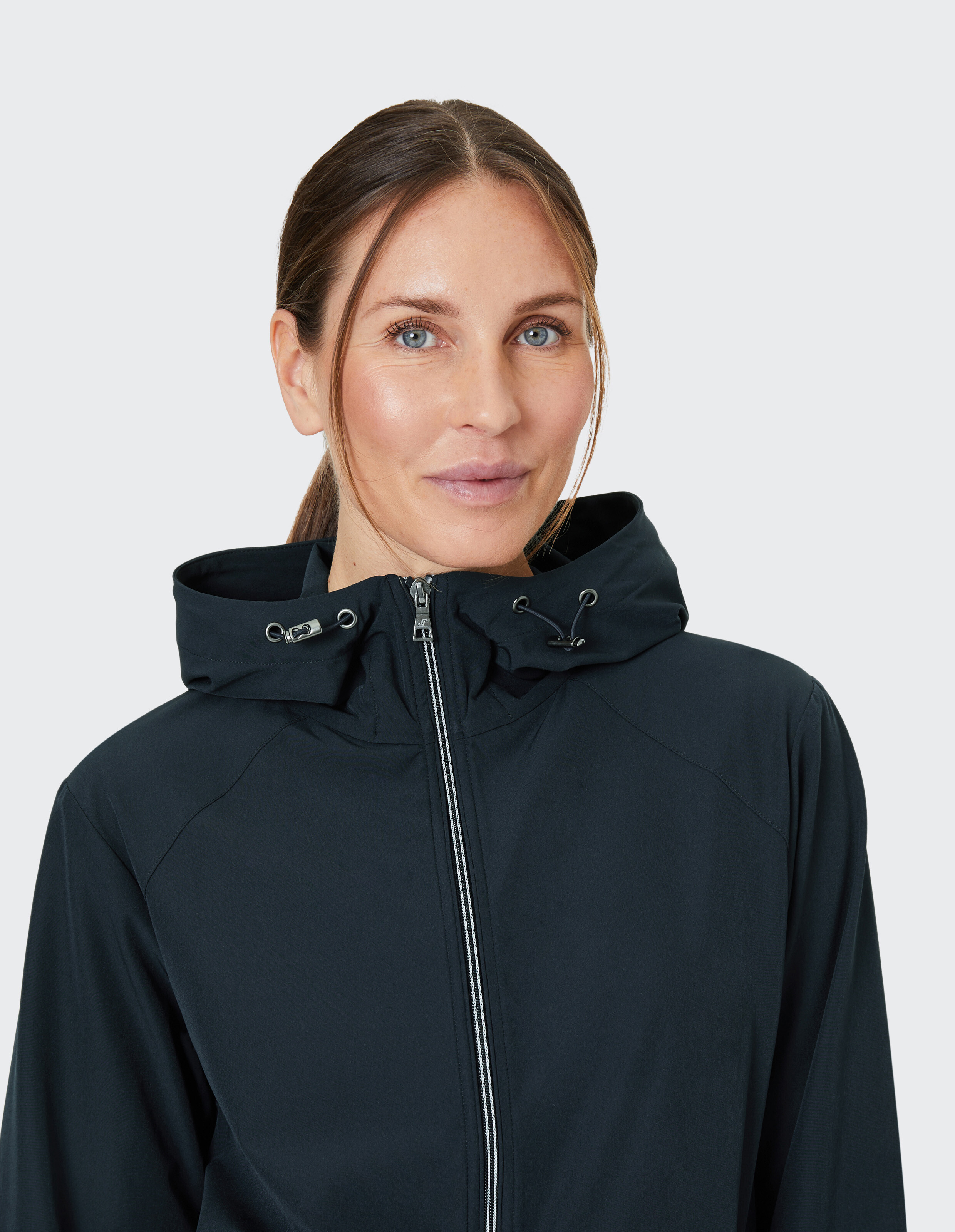 Frau trägt eine dunkelblaue, lässige Jacke mit Reißverschluss und Kapuze für Reisen oder Freizeitaktivitäten im Freien.