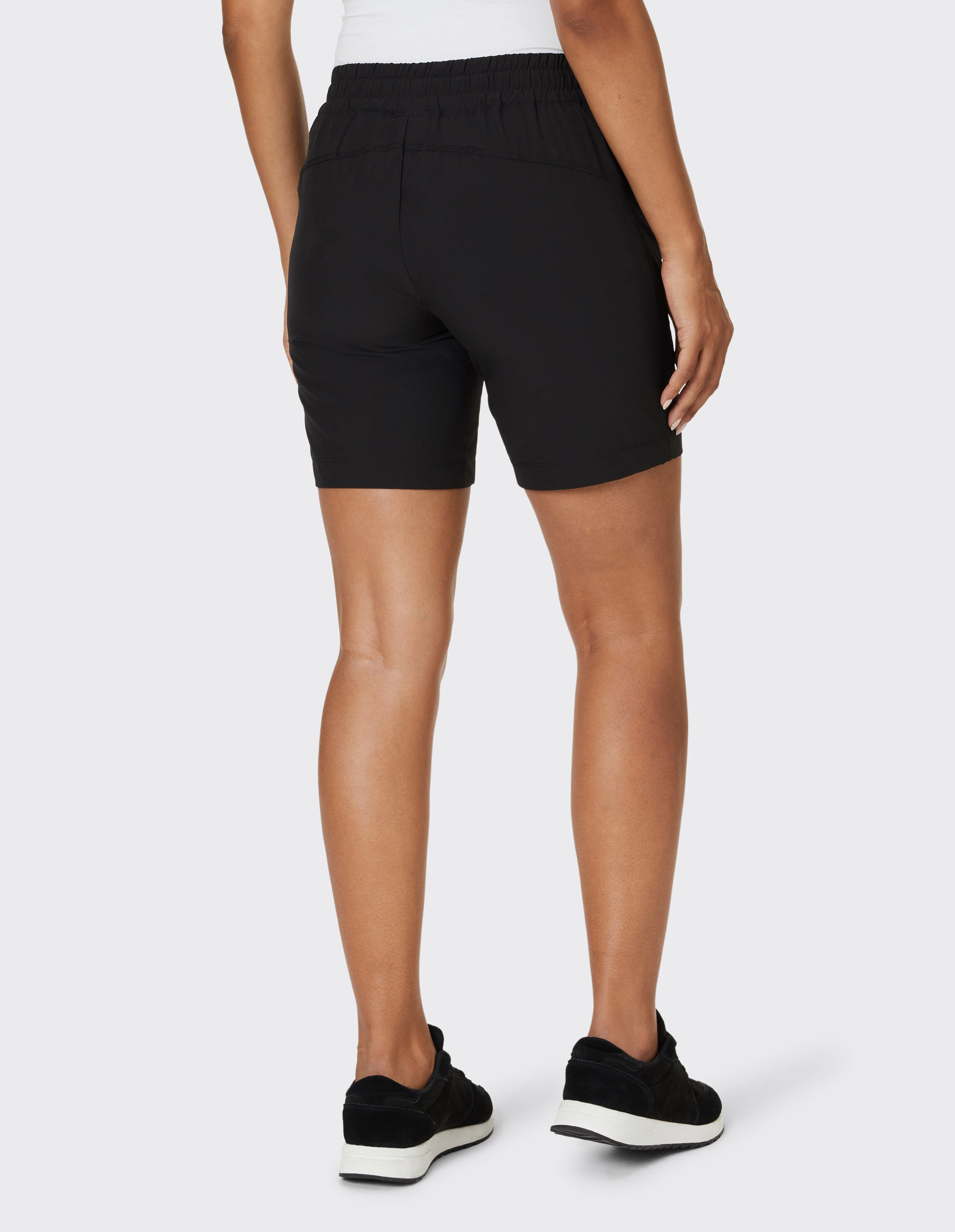 Rückansicht einer Frau in schwarzen Freizeitshorts und schwarzen Turnschuhen.