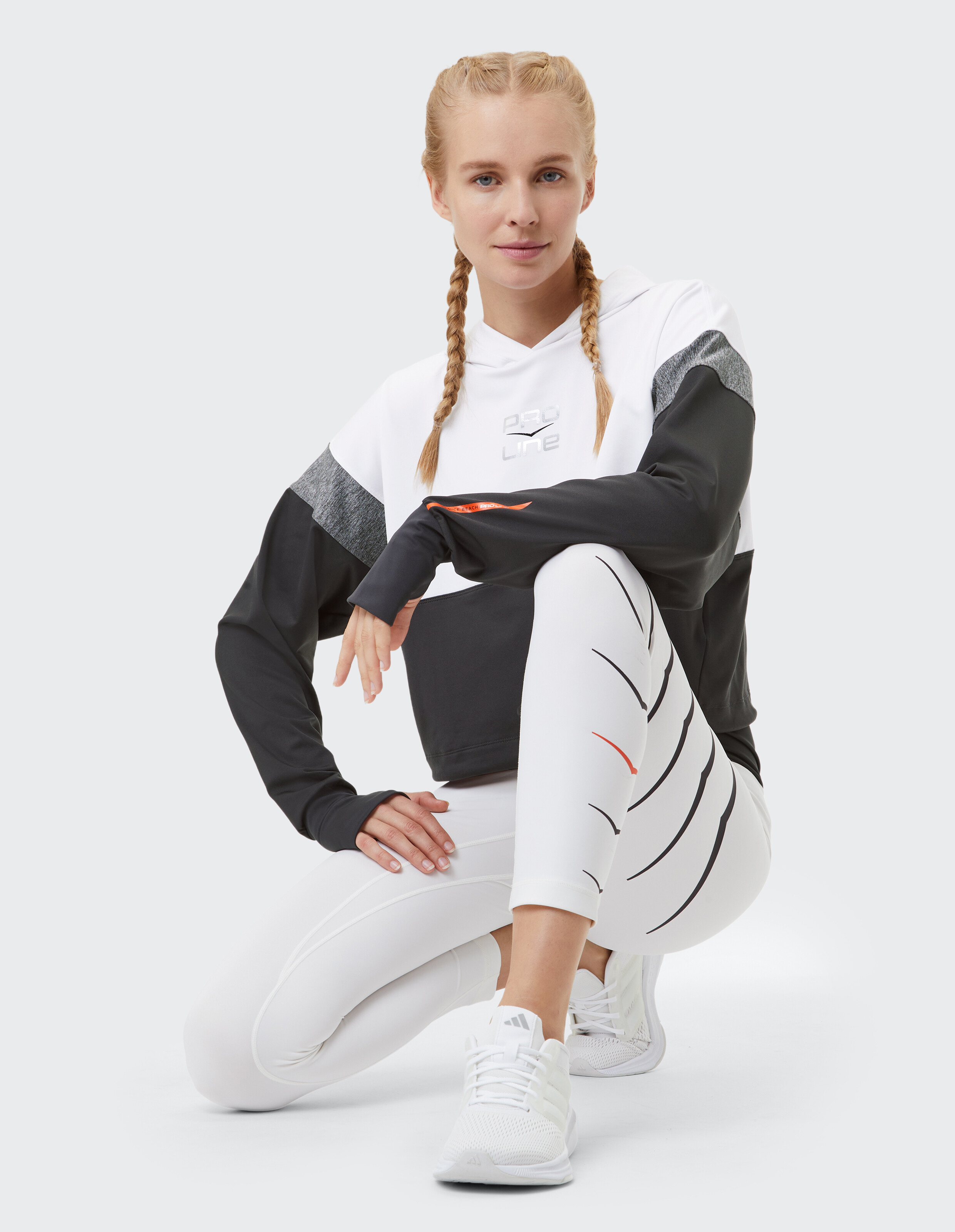 Frau in einem stylischen schwarz-weißen Kapuzenpullover mit Leggings, perfekt für Freizeitkleidung.