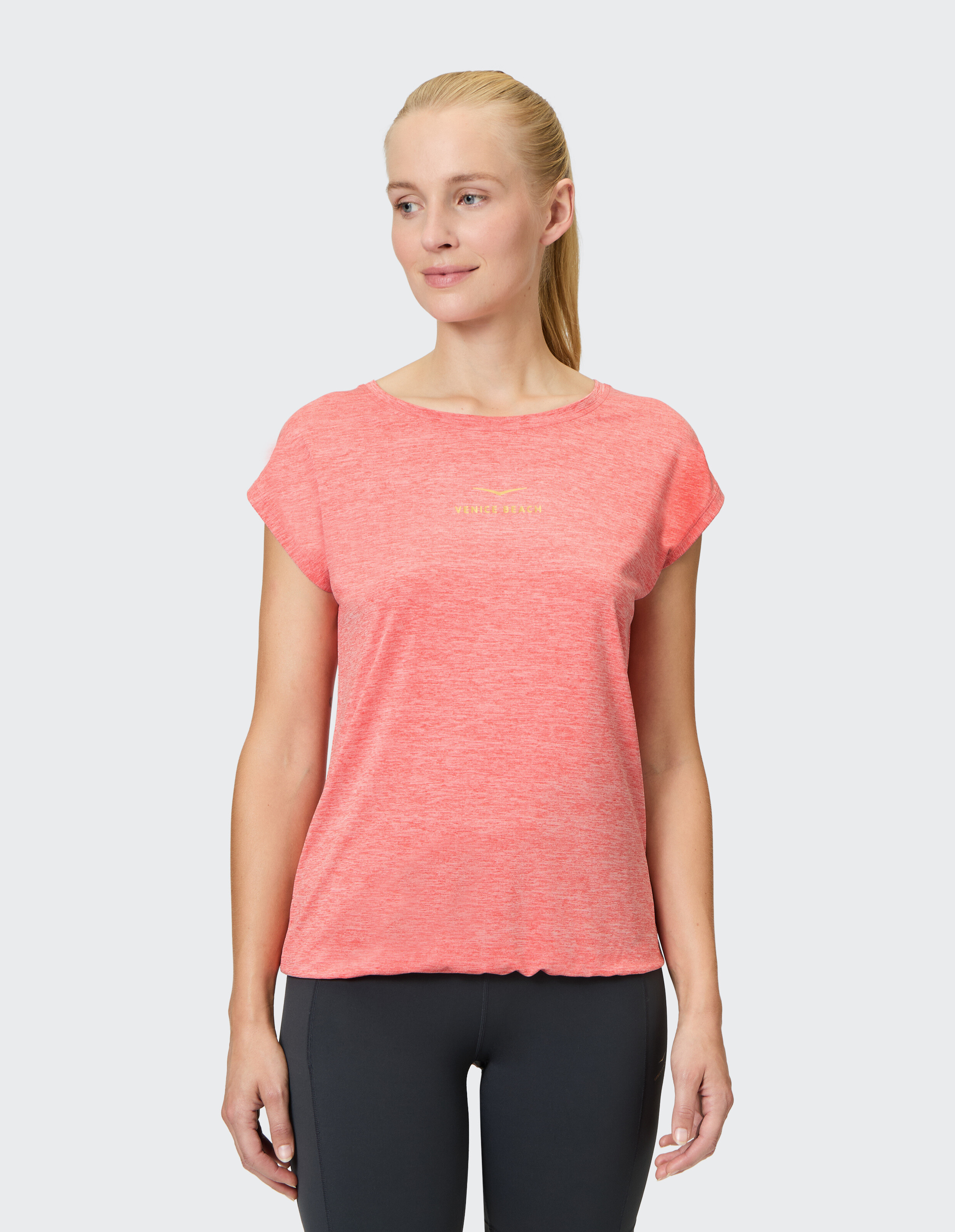 Frau in einem korallenfarbenen Freizeit-T-Shirt mit kurzen Ärmeln, perfekt zum Entspannen.