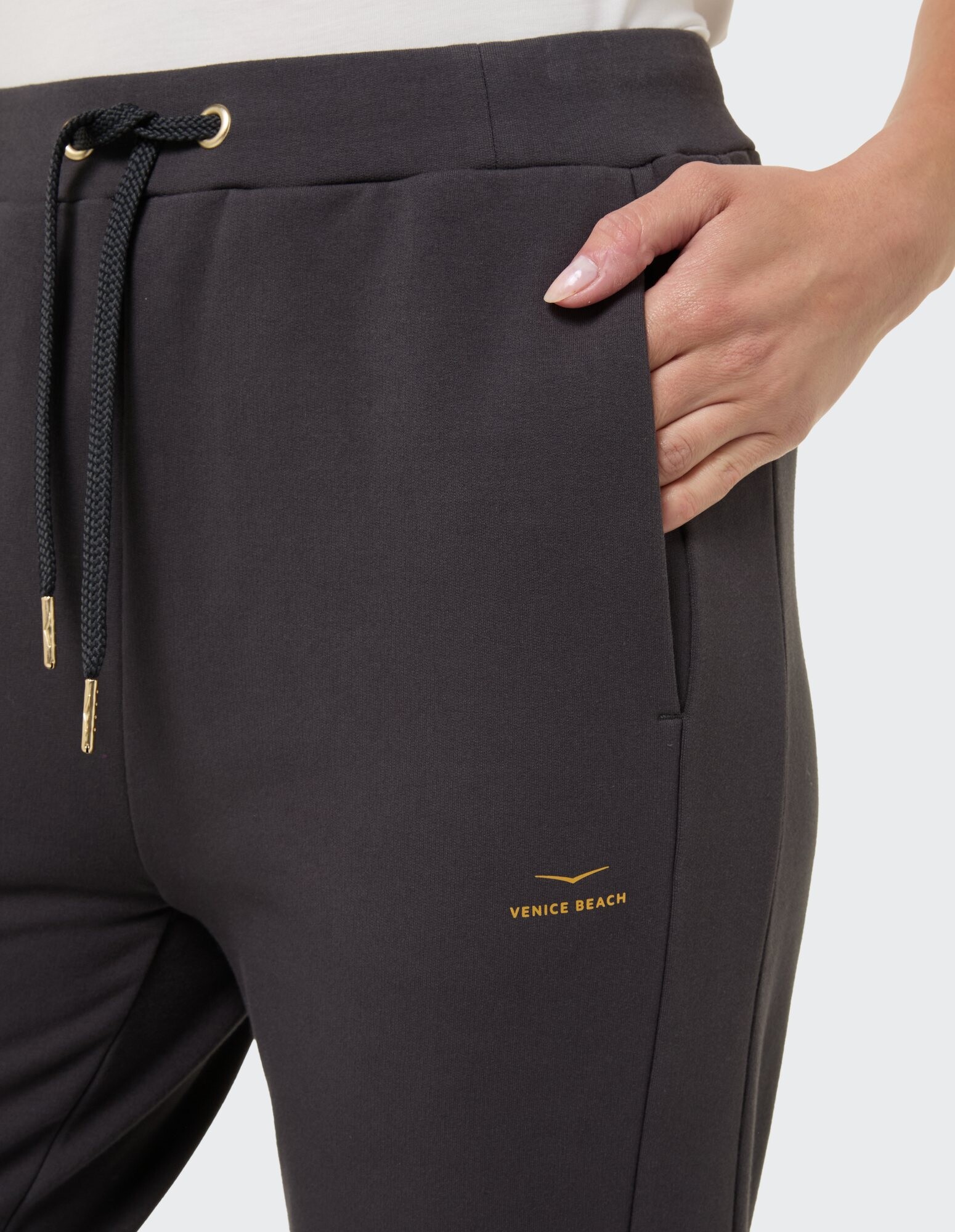 Nahaufnahme einer dunkelgrauen Jogginghose von Venice Beach mit goldenem Logo und Kordelzug.