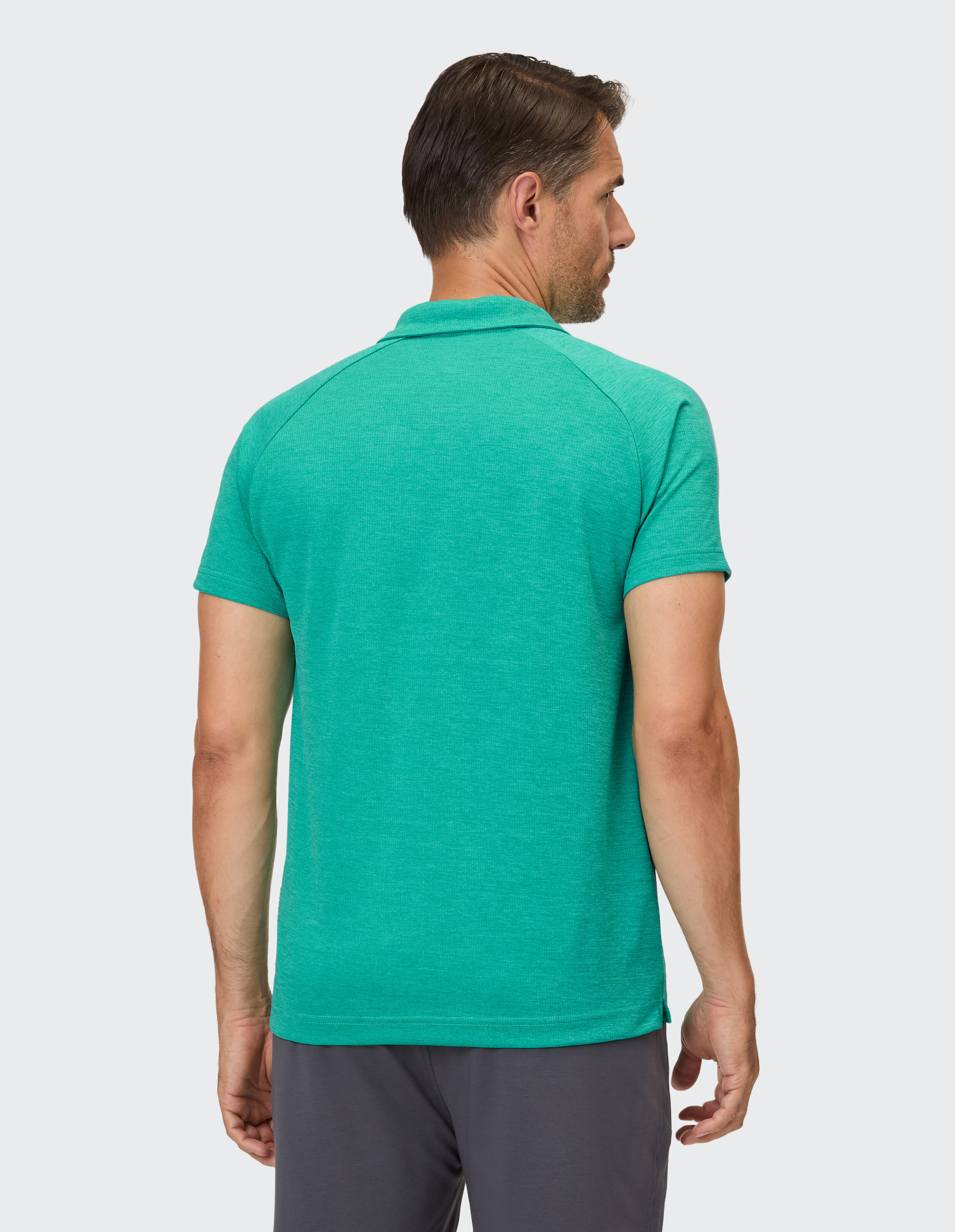 Ein Mann trägt ein smaragdgrünes Poloshirt mit kurzärmligem Kragen, das eine dezente Struktur aufweist.