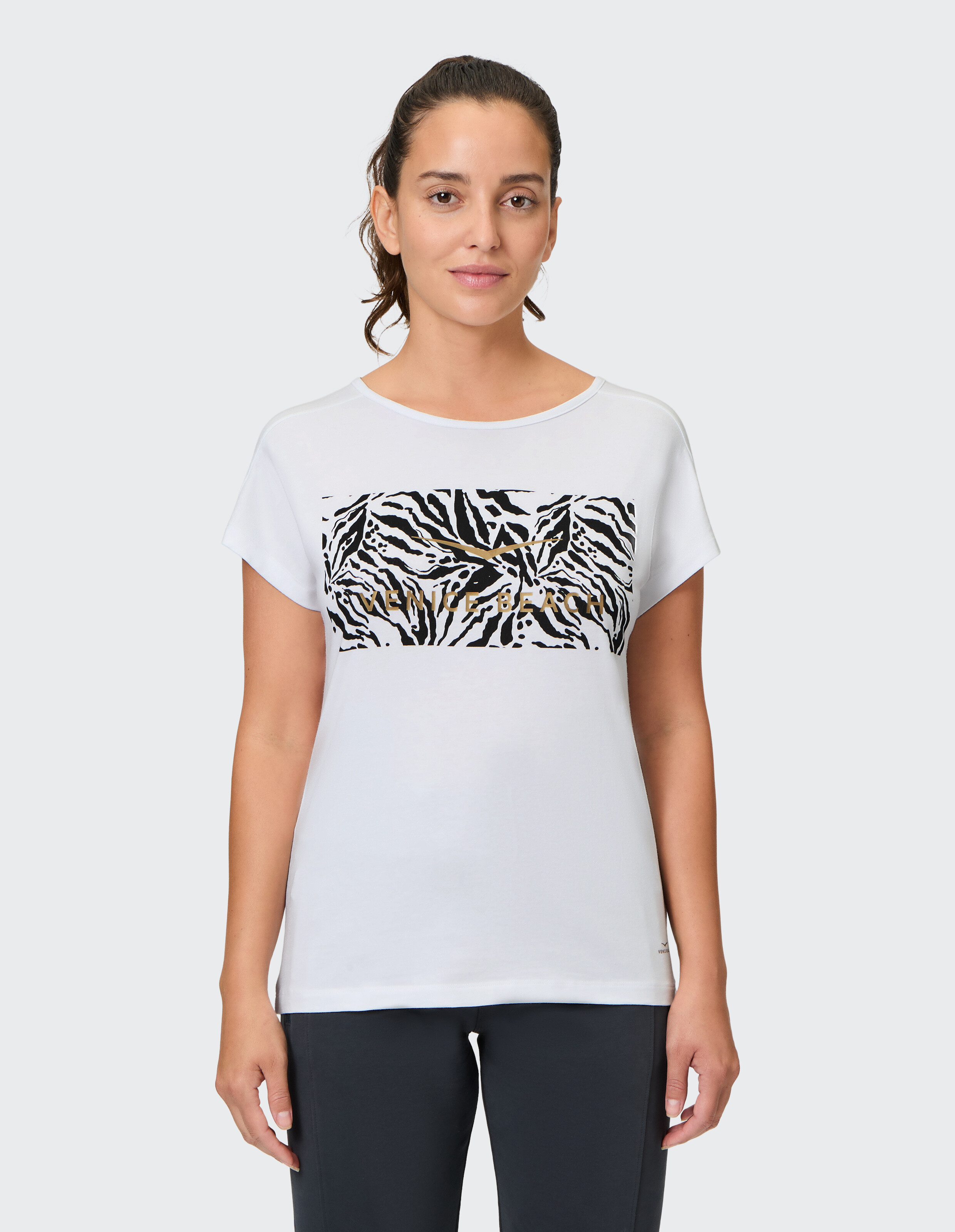 Frau trägt ein weißes Freizeit-T-Shirt mit schwarzem Zebradruck und Venice Beach-Logo.