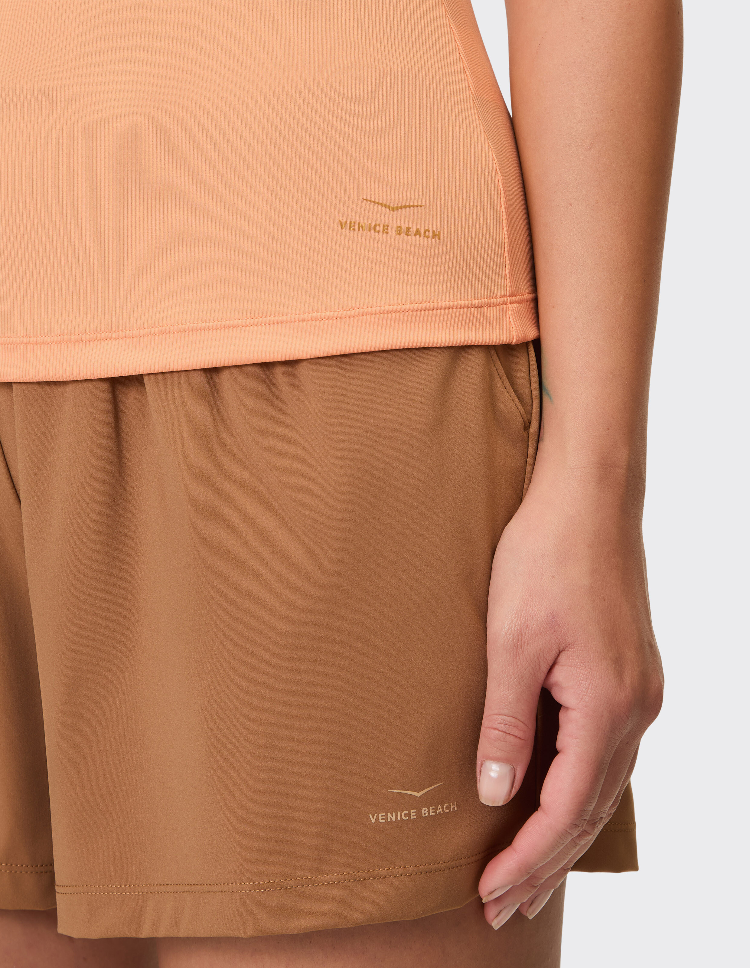 Pfirsichfarbenes, geripptes Venice Beach Brenda Tanktop gepaart mit braunen Freizeitshorts.