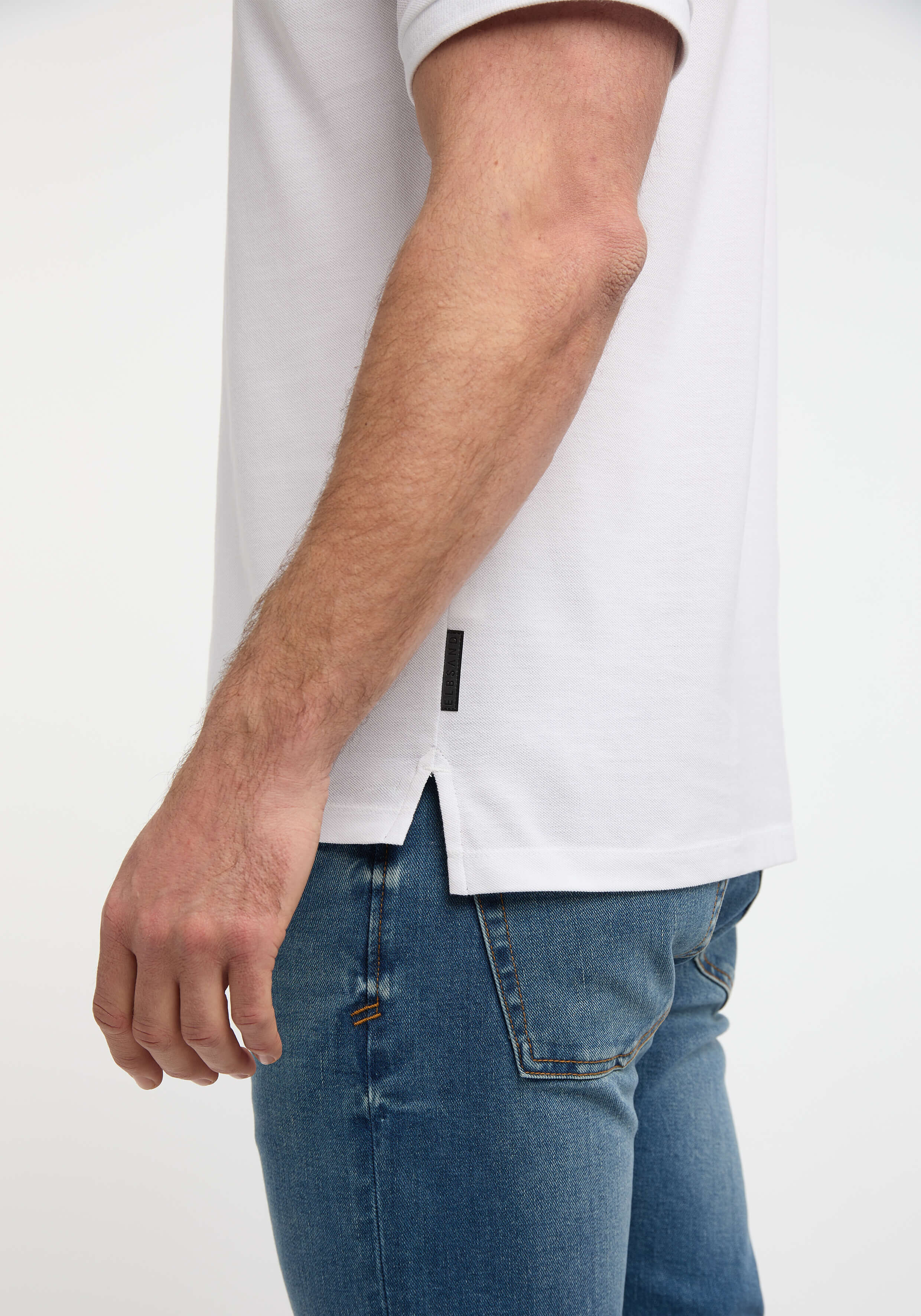 Nahaufnahme eines Mannes, der ein weißes Poloshirt mit blauen Jeans trägt und einen lässigen Stil unterstreicht.