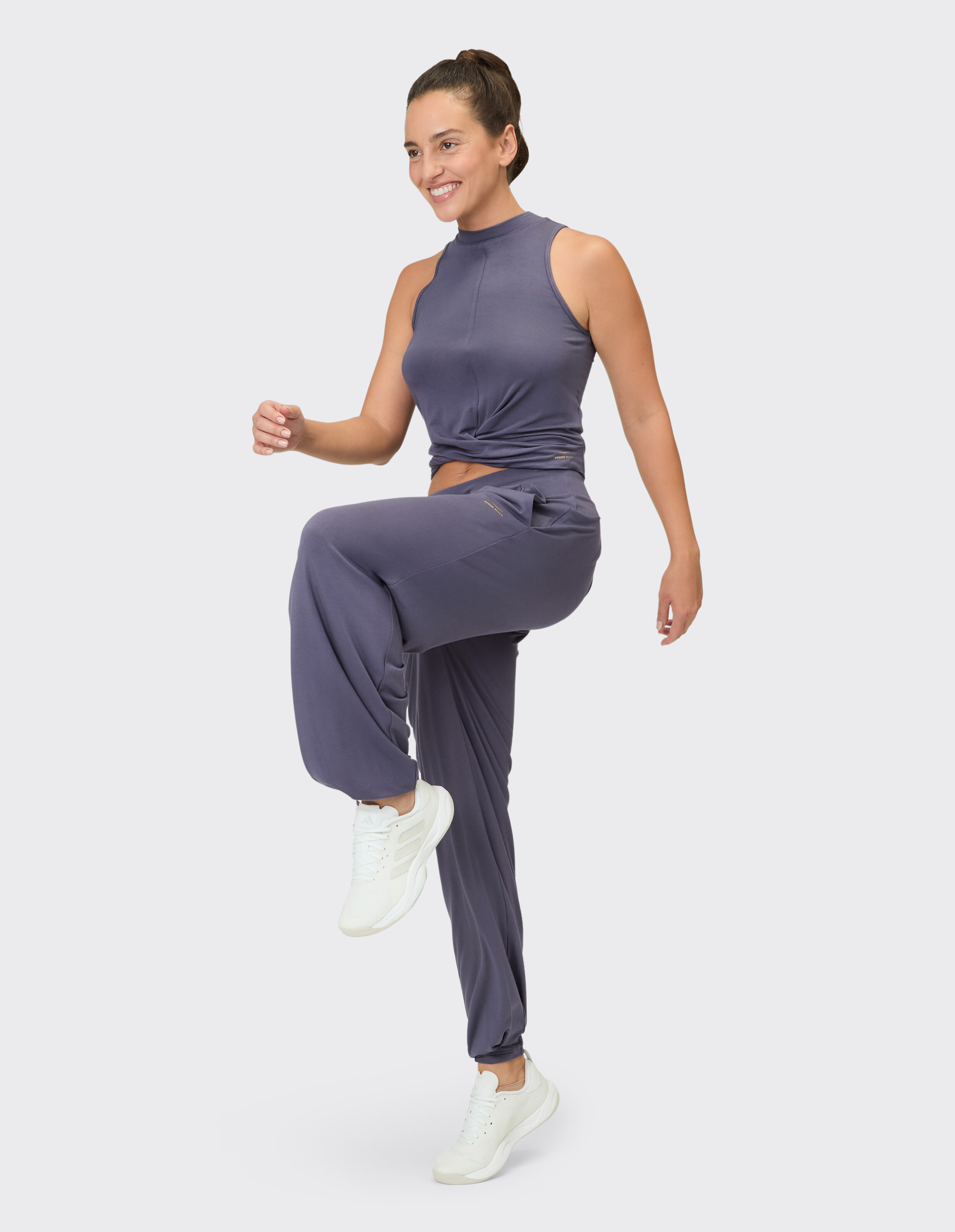 Frau in einem gemütlichen lilafarbenen Lounge-Set mit ärmellosem Oberteil und Jogginghose für Freizeitkleidung.