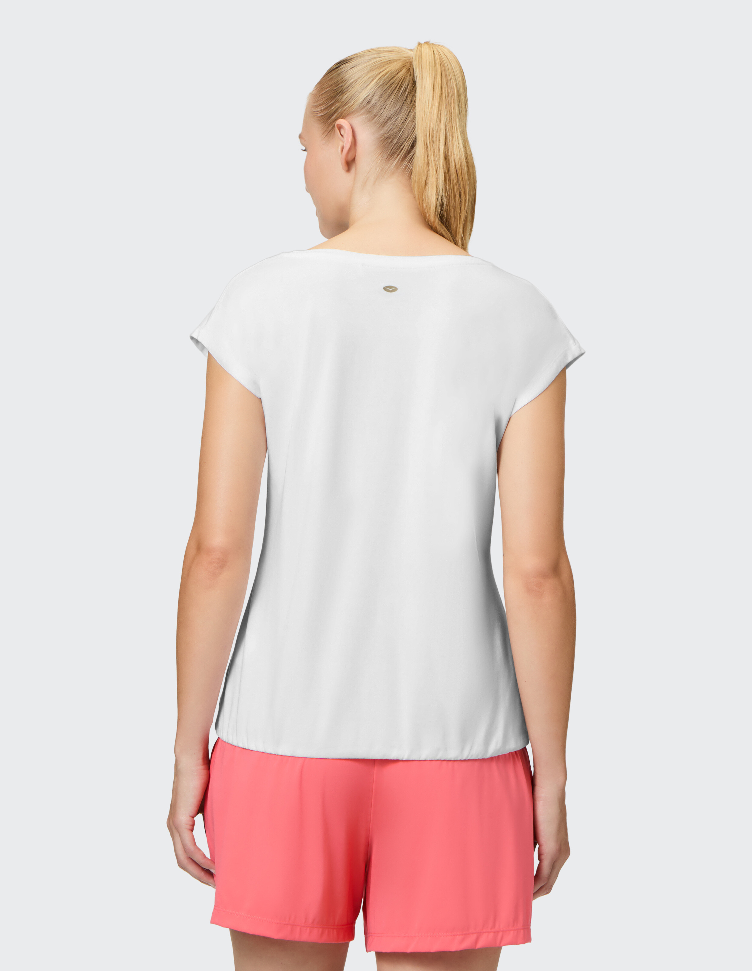 Rückansicht einer Frau, die ein weißes Freizeit-T-Shirt und rosa Shorts für einen bequemen Lounge-Look trägt.