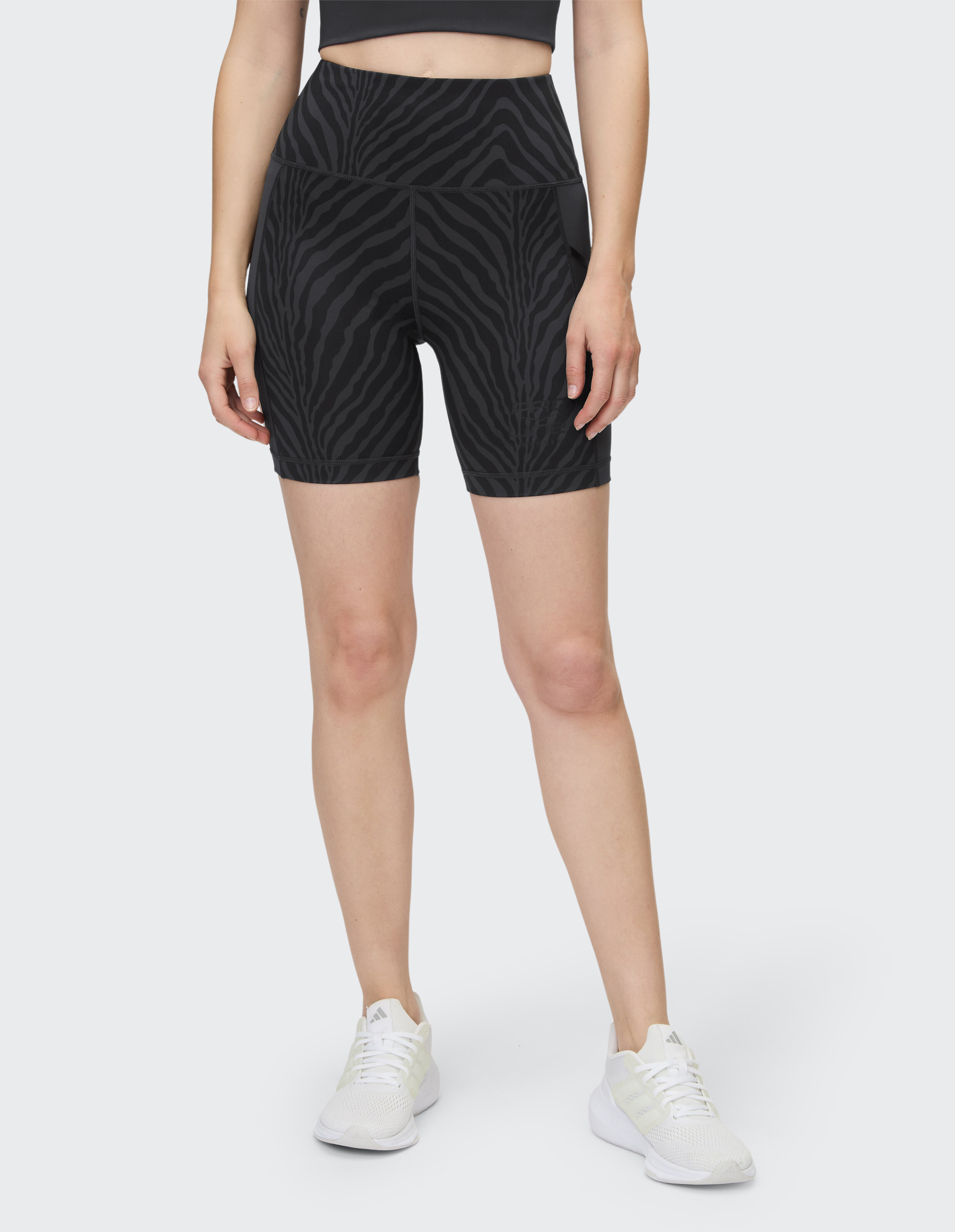 Schwarze, hoch taillierte Radlershorts mit Zebramuster, perfekt für Freizeitkleidung oder Workouts, gepaart mit weißen Turnschuhen.