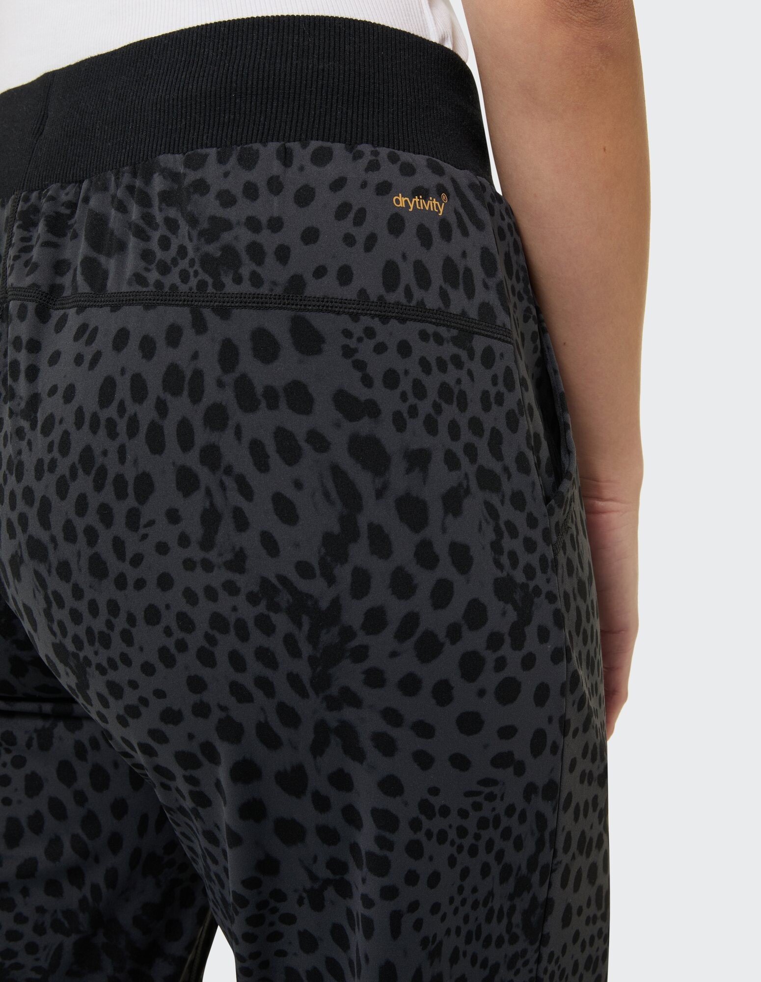 Nahaufnahme einer schwarzen Jogginghose mit Leopardenmuster, elastischem Bund und drytivity-Logo.