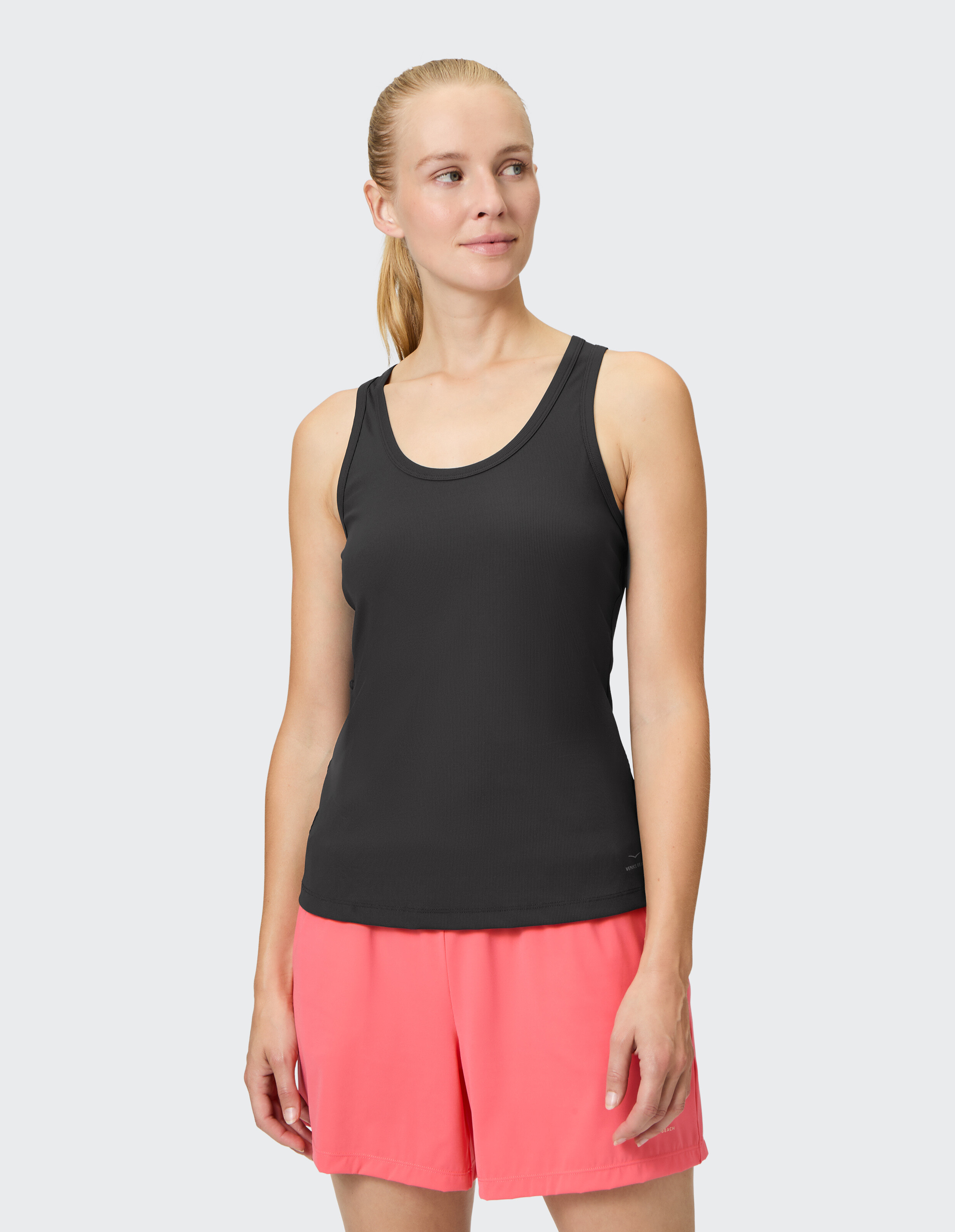 Frau trägt ein schwarzes Tanktop und rosa Freizeitshorts zum Faulenzen oder als Sportkleidung.