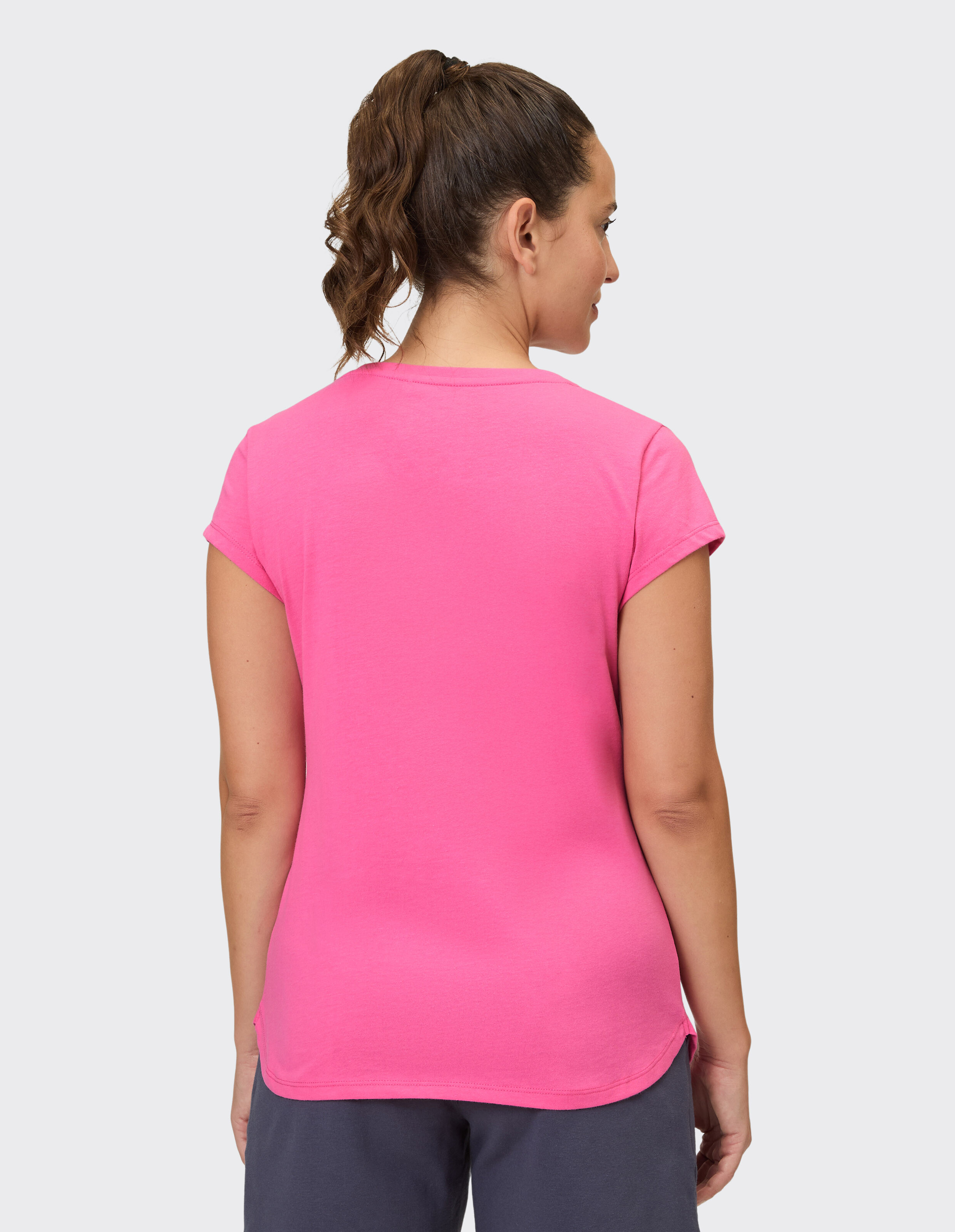 Rückansicht einer Frau, die ein leuchtend rosa lässiges T-Shirt trägt, perfekt zum Entspannen.