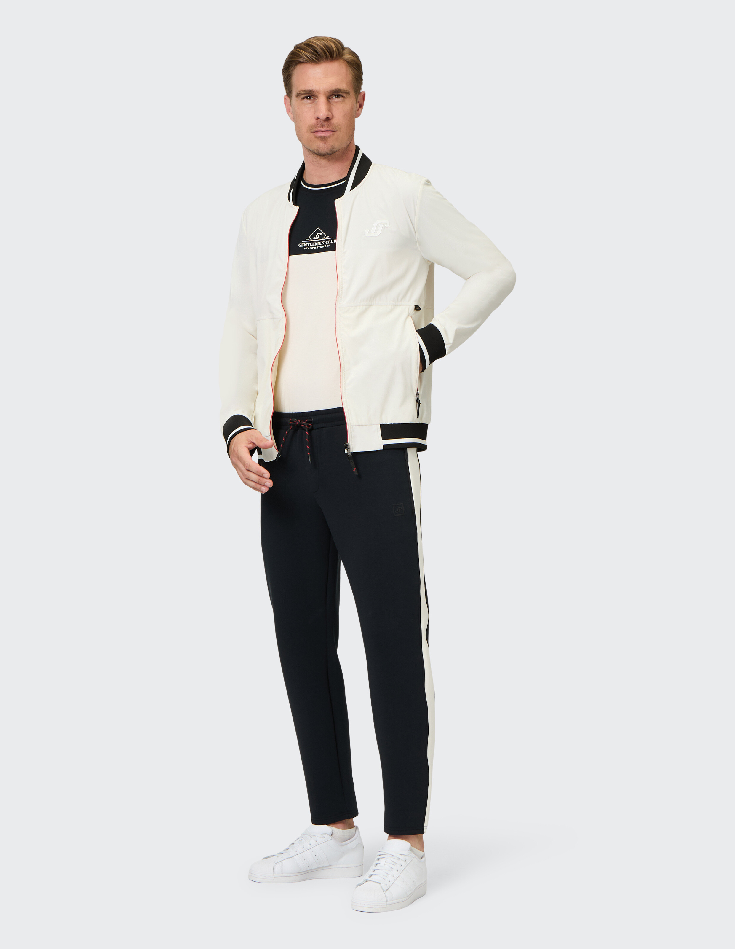 Mann trägt eine weiße Bomberjacke und eine schwarze Freizeit-Jogginghose für einen sportlichen, bequemen Look.