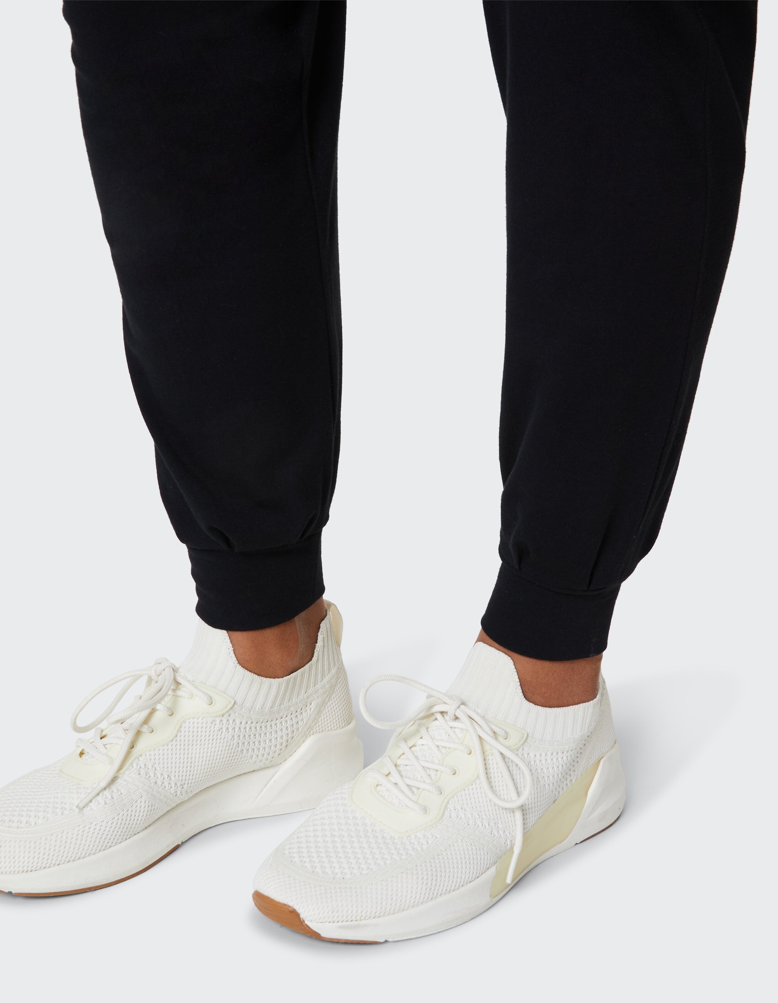 Nahaufnahme einer schwarzen Jogginghose gepaart mit weißen sportlichen Sneakers, ideal für Freizeitkleidung.