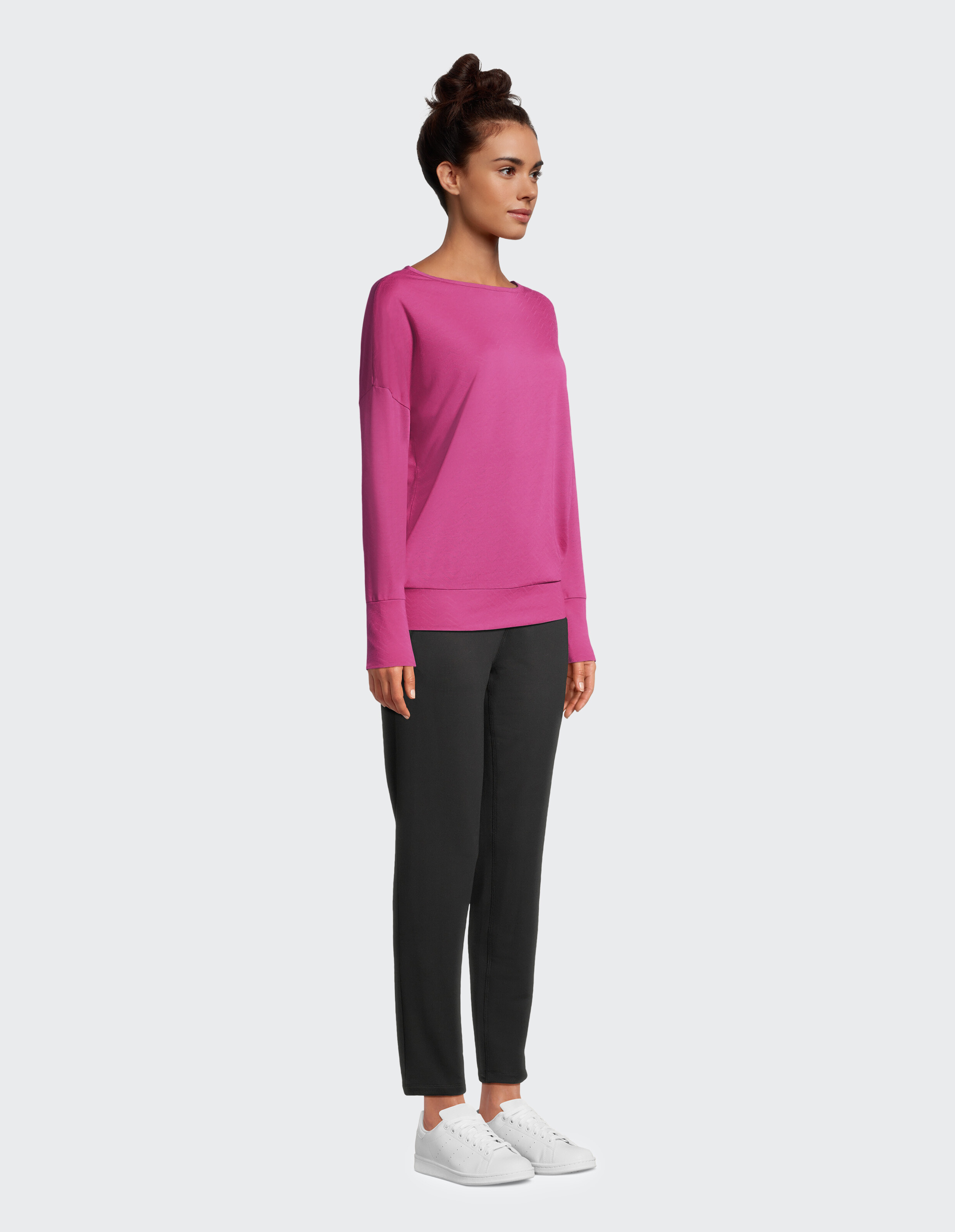 Frau trägt ein kuscheliges rosa Langarmshirt und eine schwarze Freizeithose.