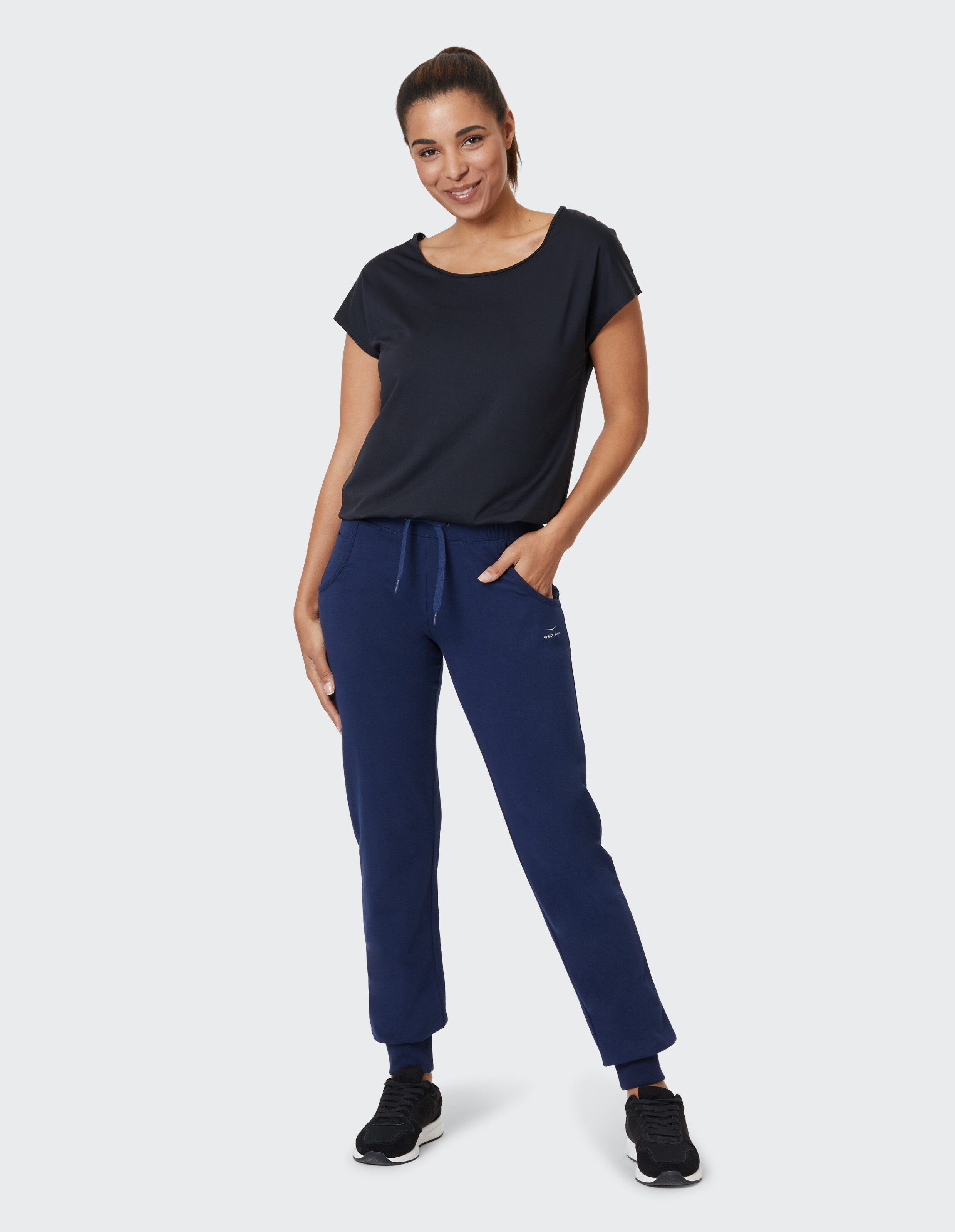 Frau in marineblauer Freizeitkleidung mit lockerem Oberteil und Jogginghose.
