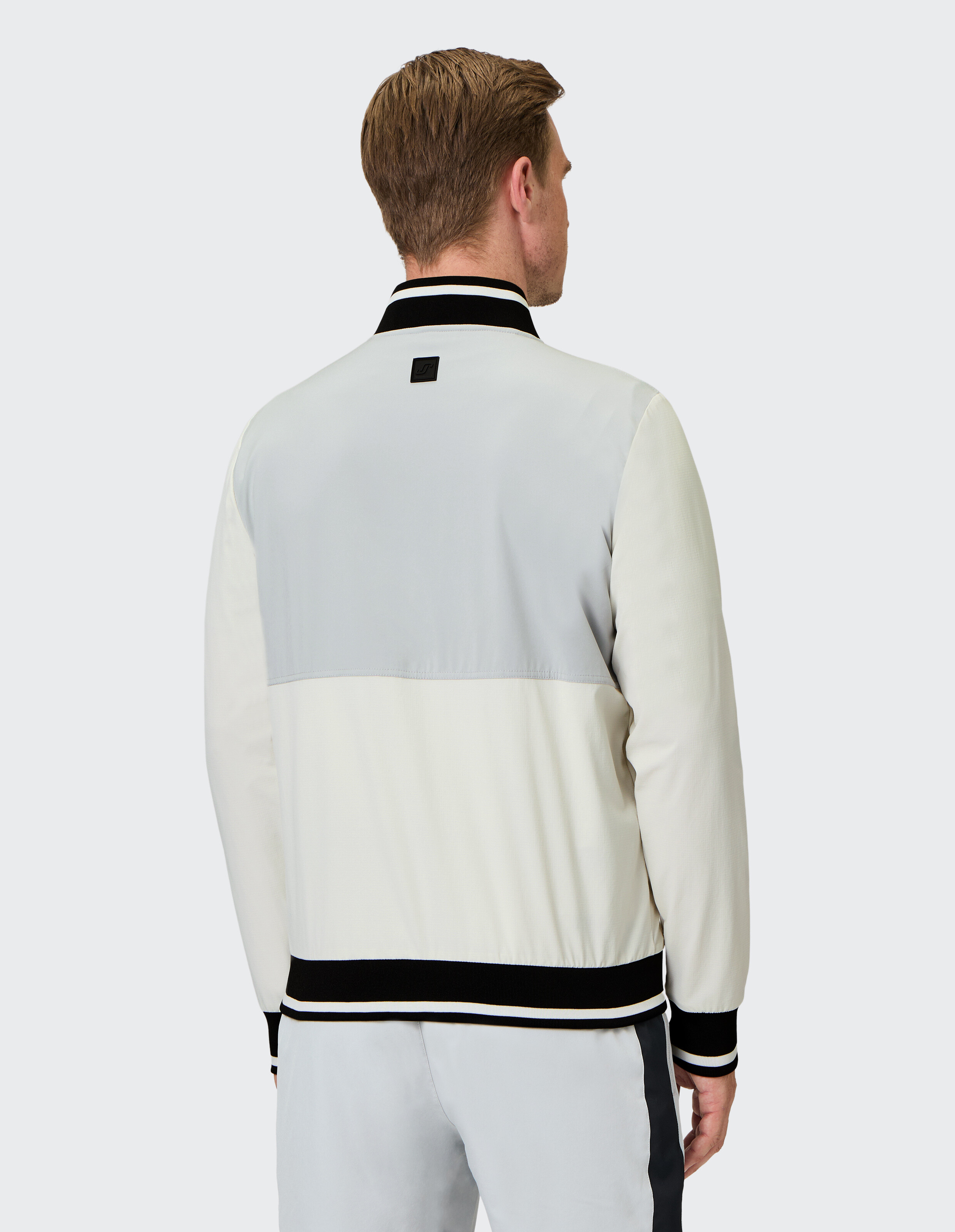 Mann trägt eine lässige Bomberjacke in Colour-Block-Optik mit gestreiftem Rippstrickbesatz.
