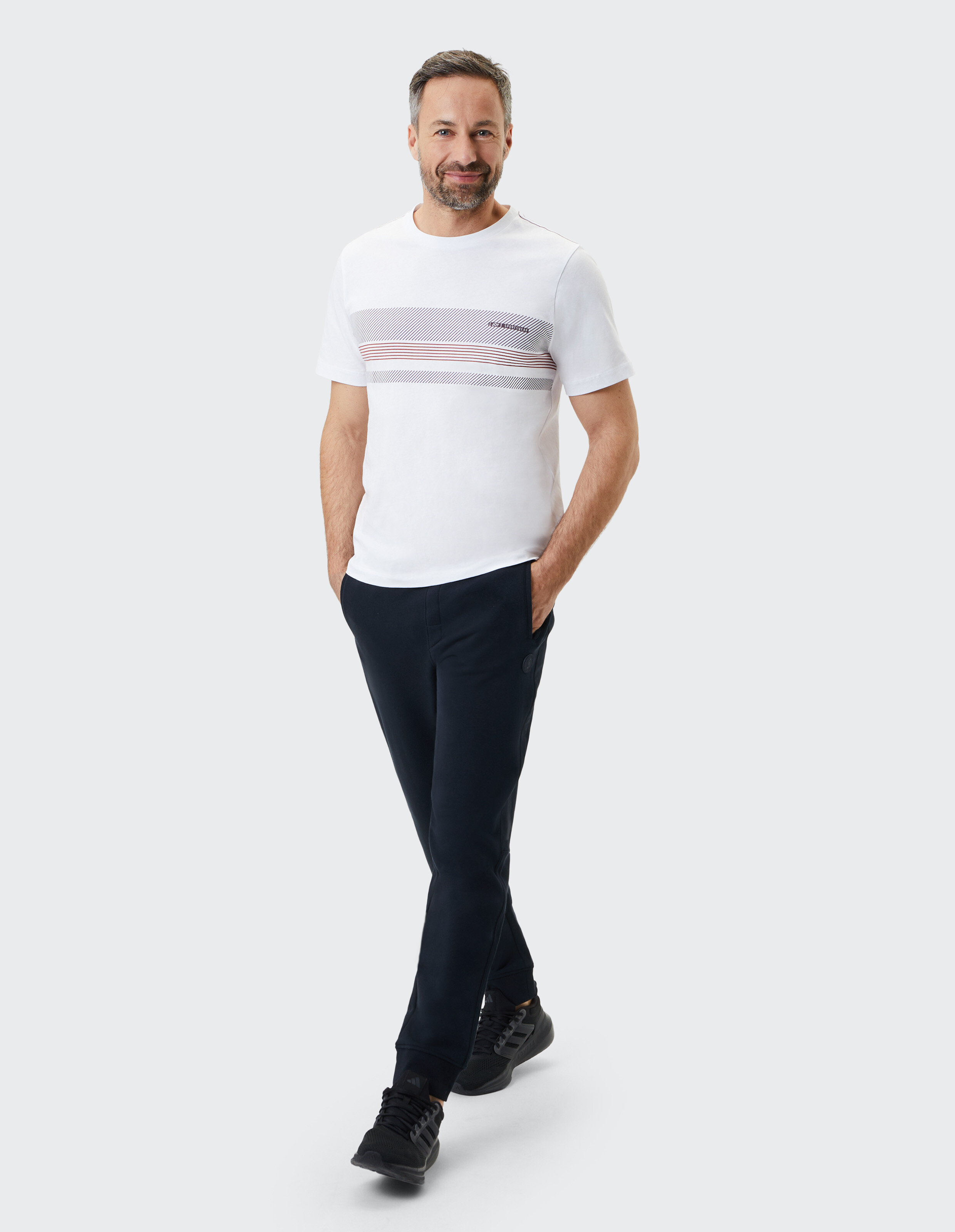 Mann in einem weiß gestreiften T-Shirt und einer dunkelblauen Hose, der lässigen Stil zeigt.