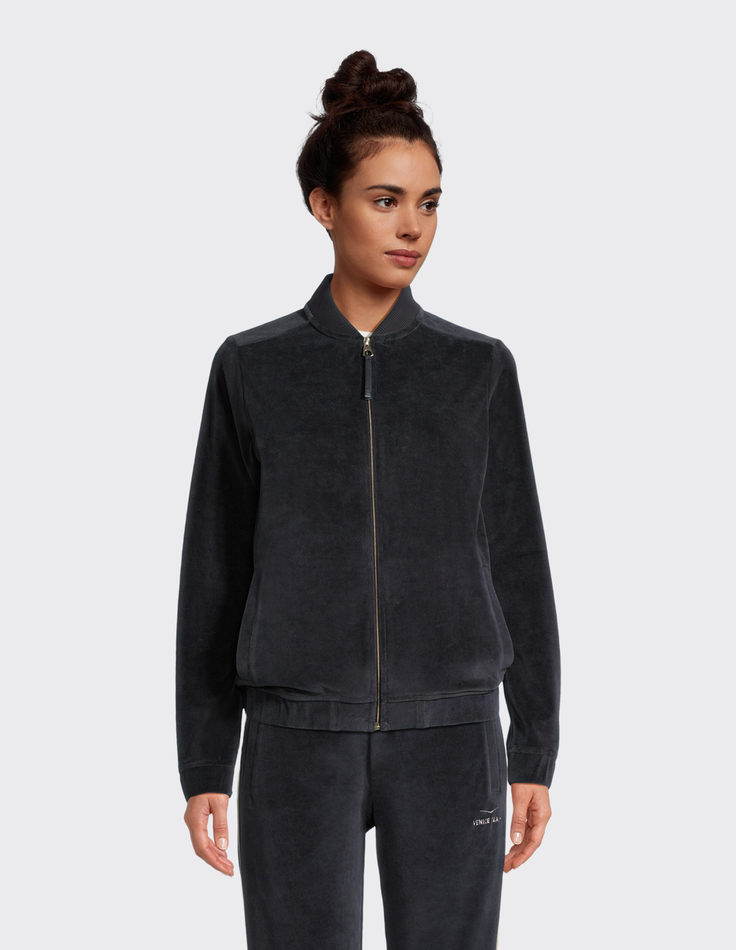 Frau trägt eine gemütliche dunkelgraue Velours-Bomberjacke mit Reißverschluss für lässige Loungewear.