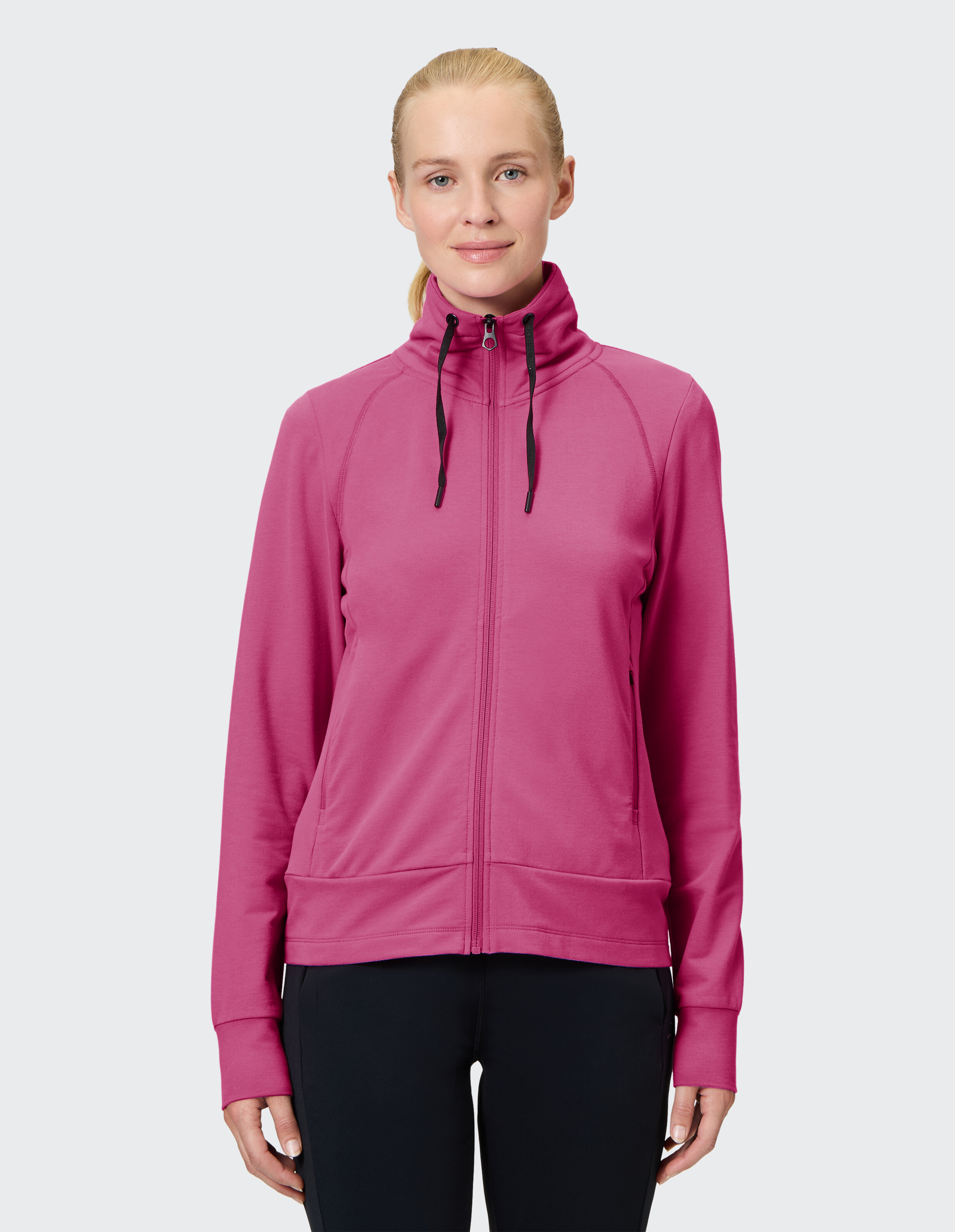Frau trägt ein kuscheliges rosa Sweatshirt mit Reißverschluss und hohem Kragen für lässige Reisekleidung.