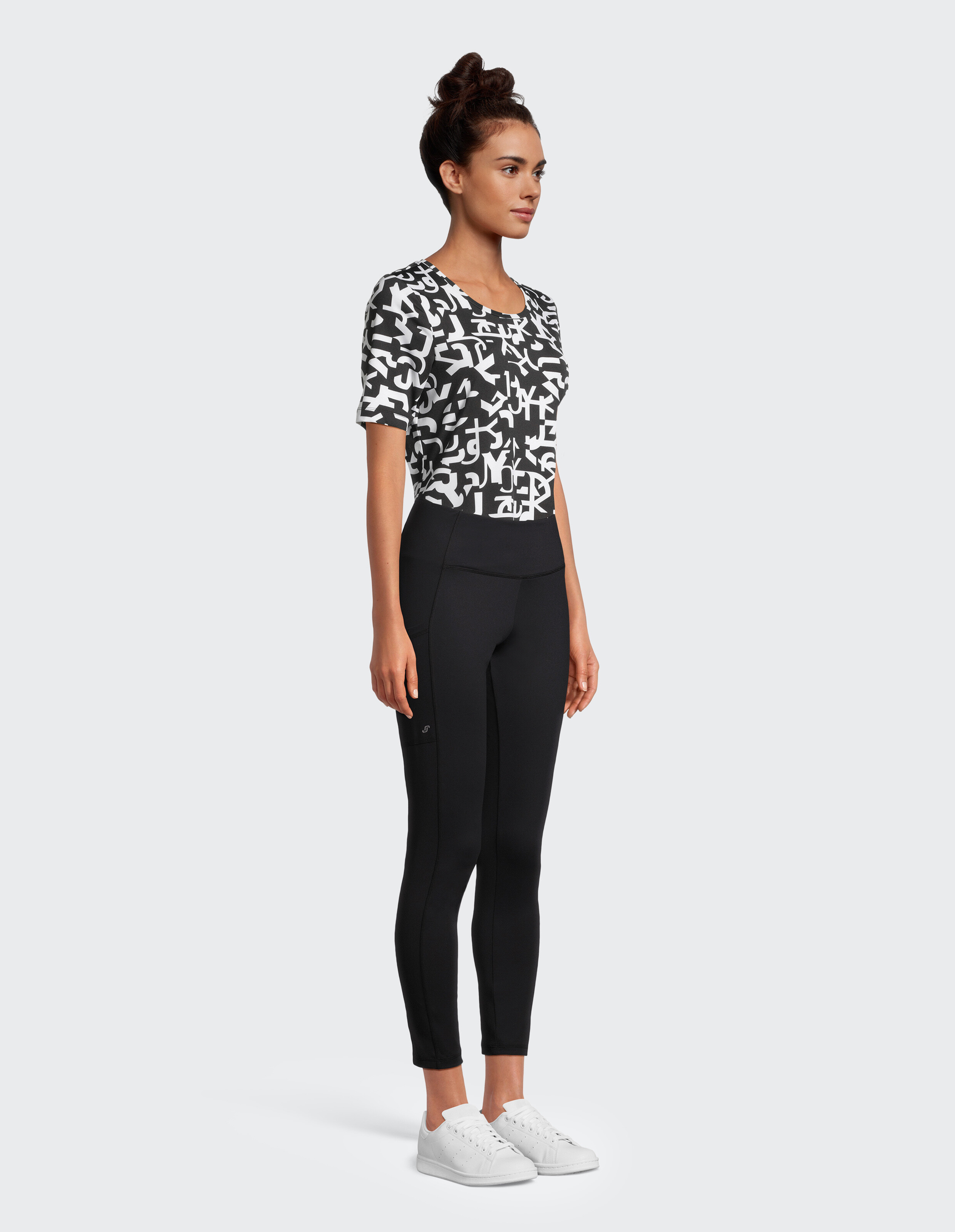Frau trägt ein schwarz-weiß gemustertes T-Shirt und schwarze Leggings für Freizeitkleidung.
