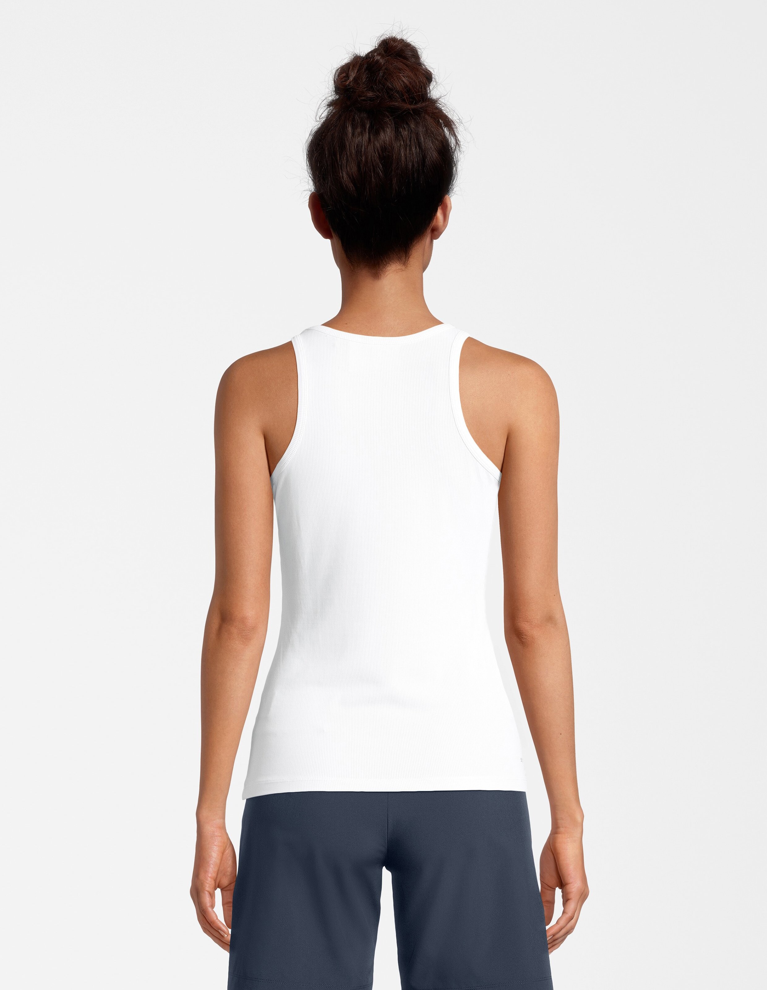 Rückansicht einer Frau in einem weißen Tanktop und dunkelblauen Shorts, die einen lässigen Stil unterstreicht.