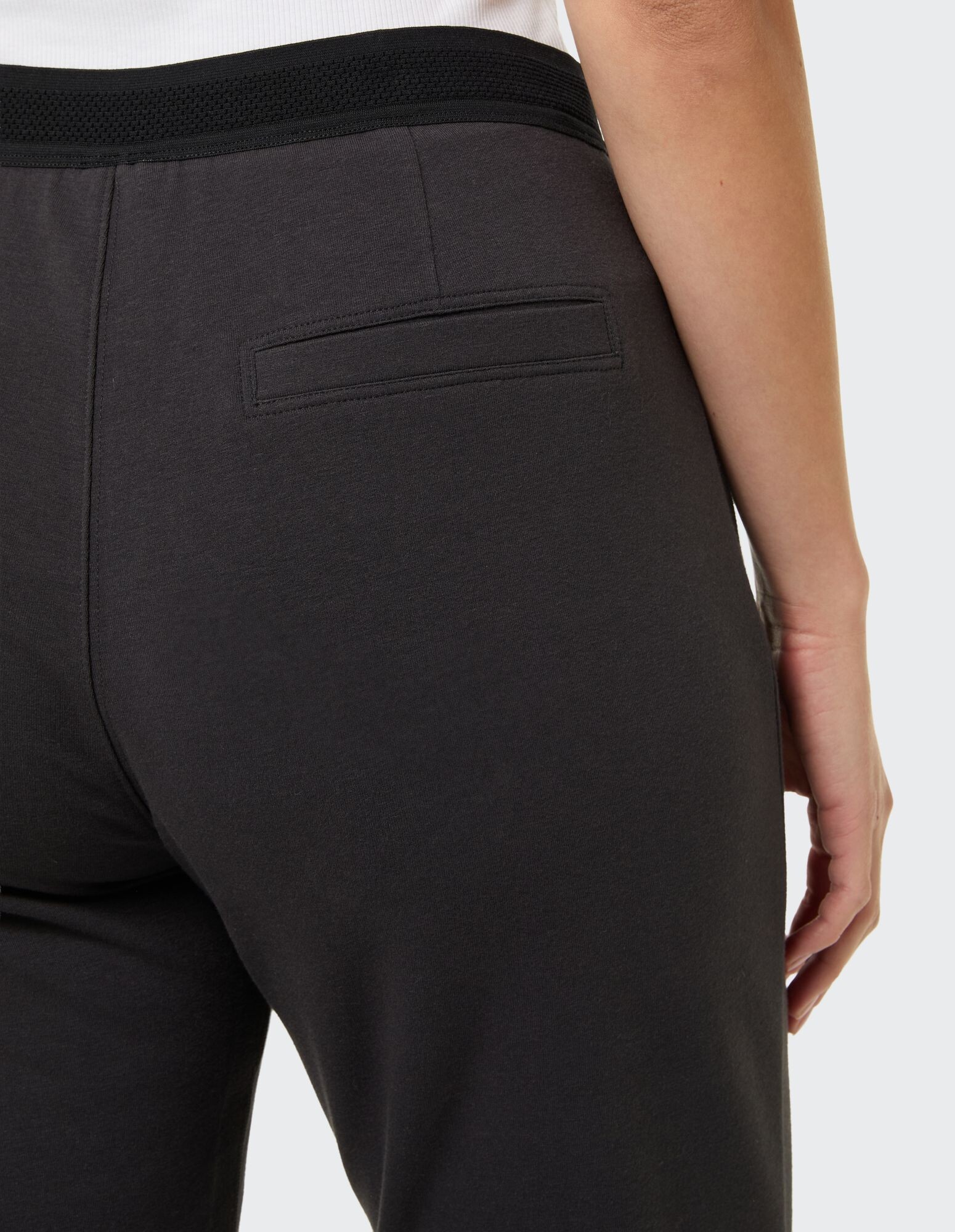 Nahaufnahme einer schwarzen Freizeithose mit Gesäßtasche und elastischem Bund.