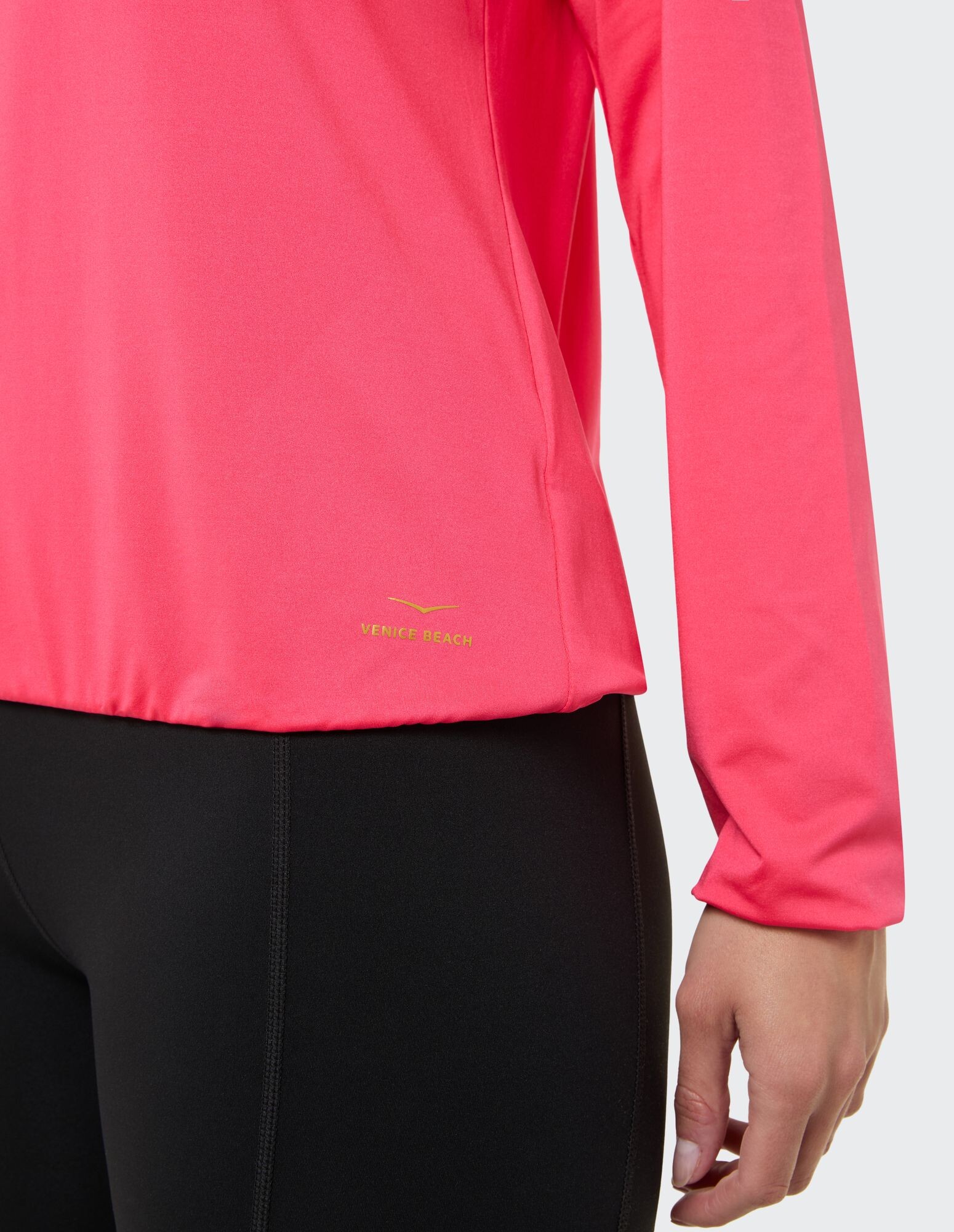 Nahaufnahme eines rosafarbenen Langarmoberteils gepaart mit schwarzen Leggings, Freizeitkleidung.