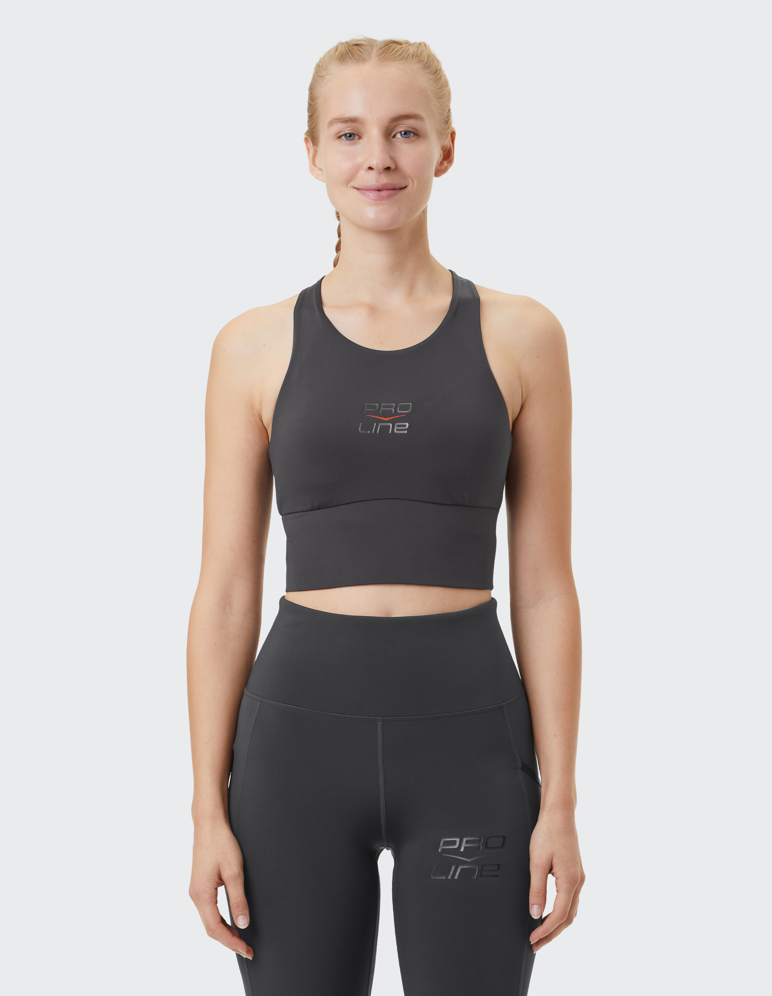 Frau trägt ein dunkelgraues, sportliches Crop-Top und Leggings für lässige Fitness.