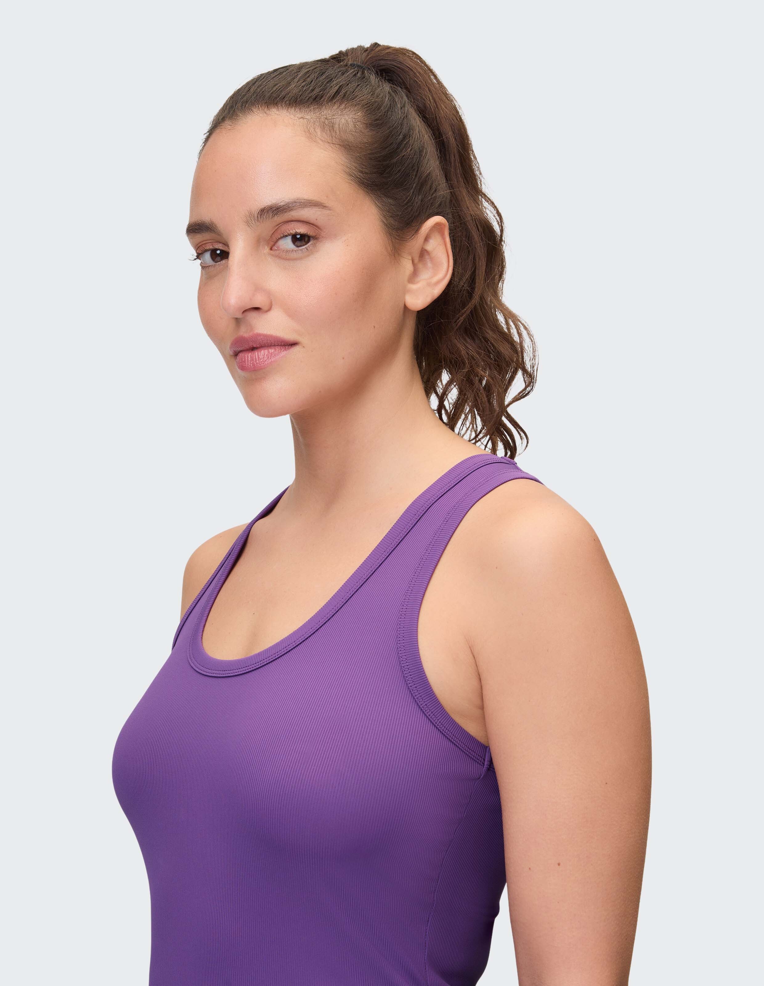 Seitenansicht einer Frau in einem lila Tanktop, das einen lässigen und bequemen Stil unterstreicht.