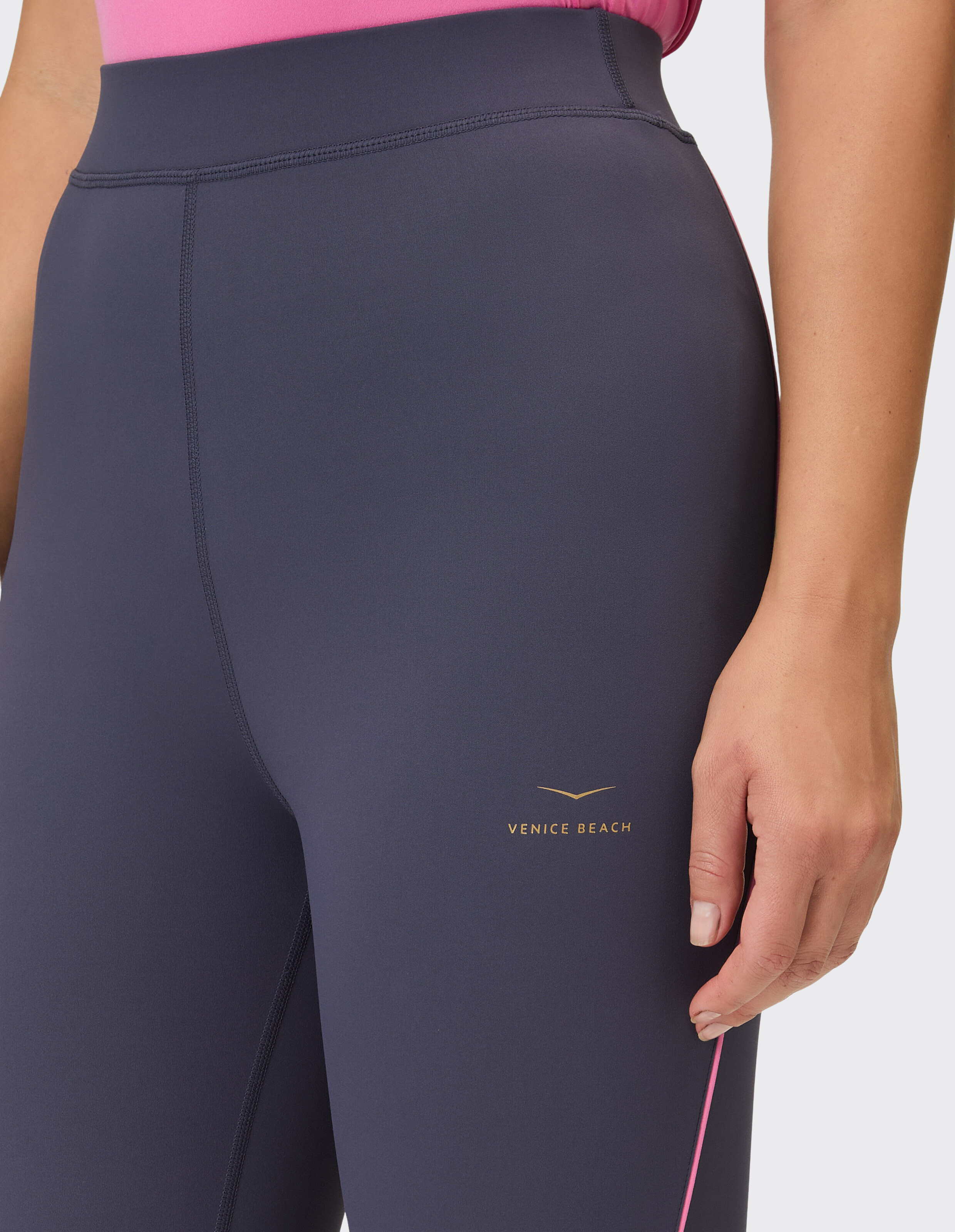 Nahaufnahme einer dunkelgrauen, hoch taillierten Venice Beach-Leggings mit rosa Besatz.