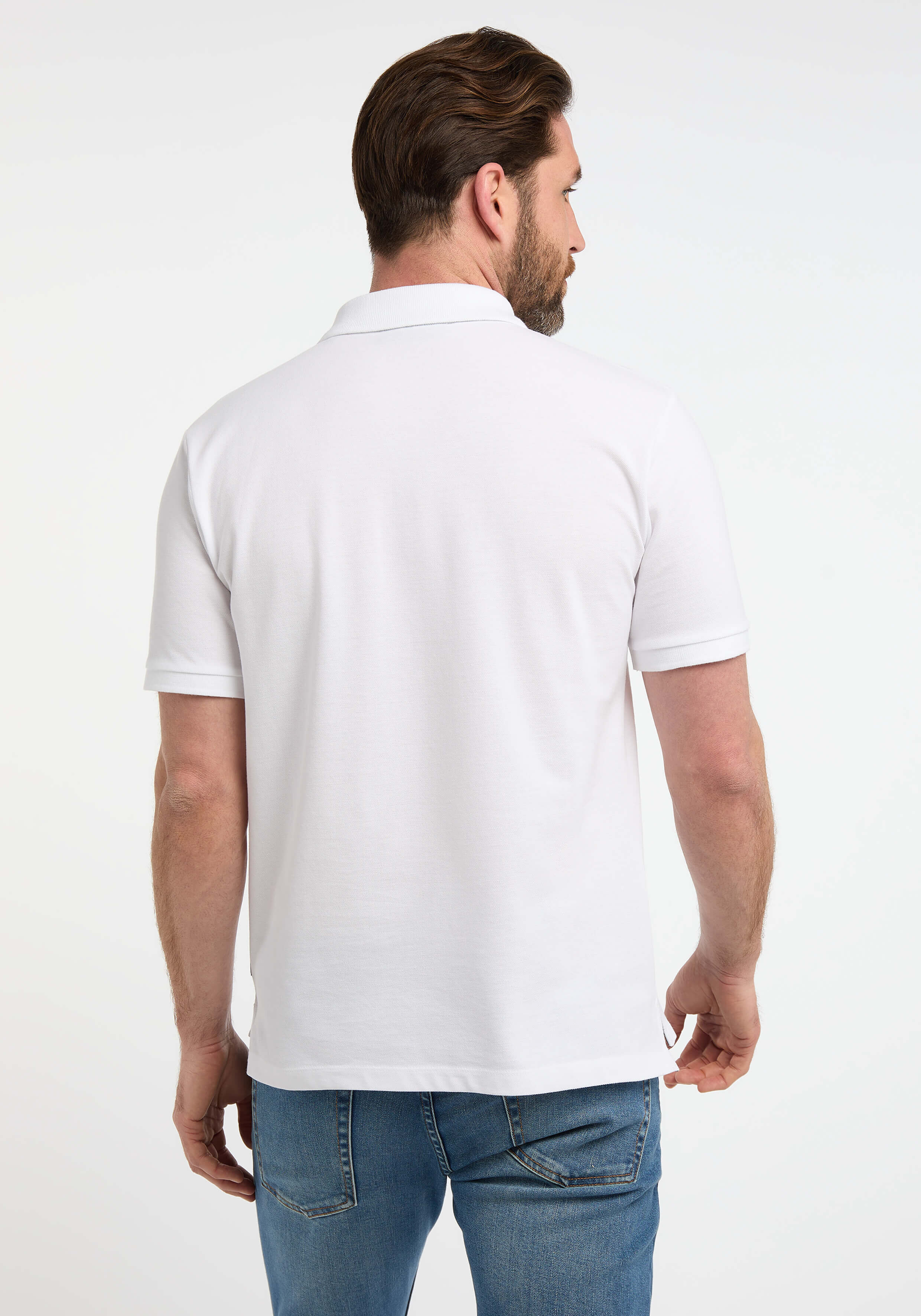Rückansicht eines Mannes in einem weißen Poloshirt und blauen Jeans, der seinen lässigen Stil unterstreicht.