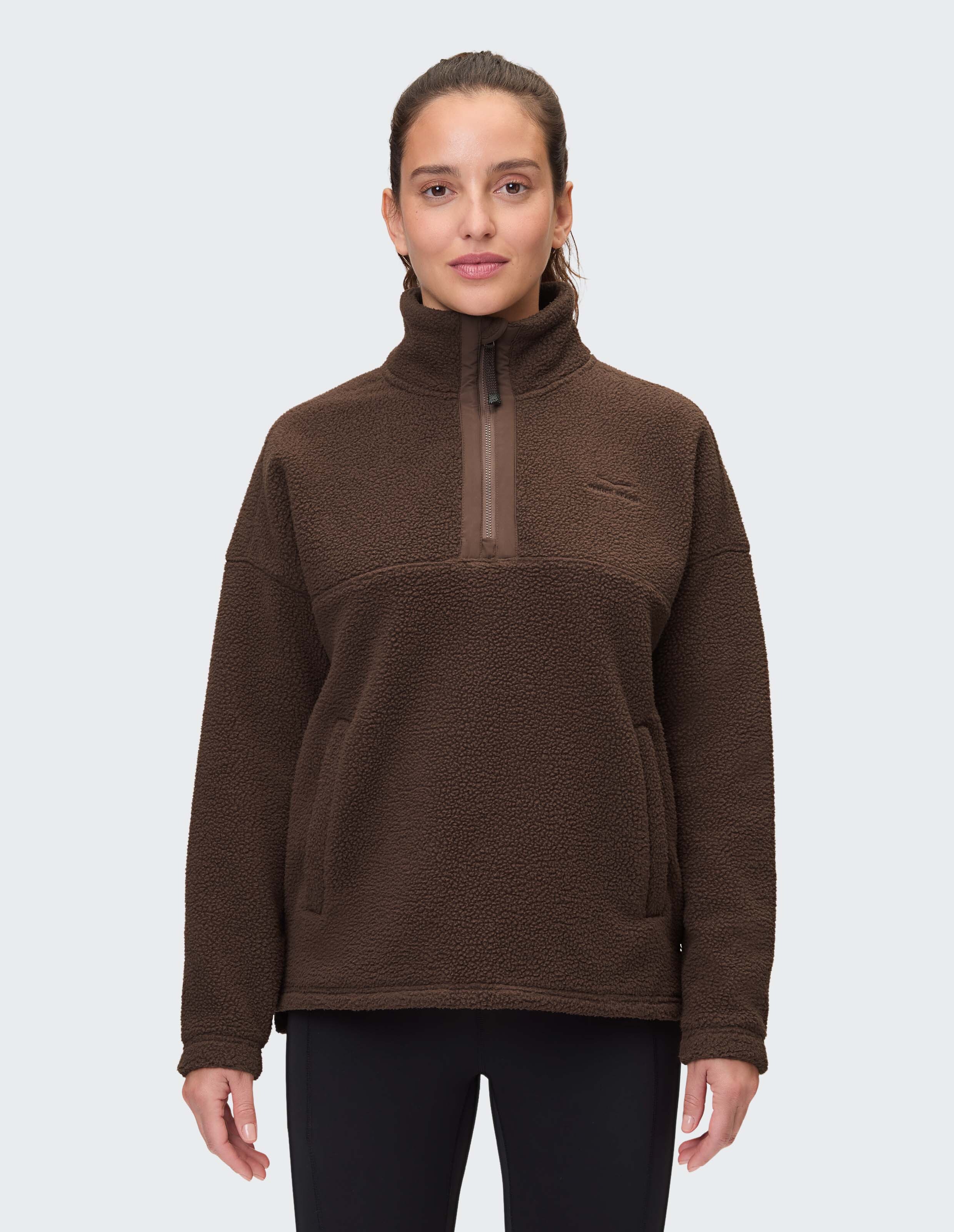 Frau trägt einen kuscheligen braunen Fleecepullover mit Kragen mit halbem Reißverschluss für lässige Loungewear.