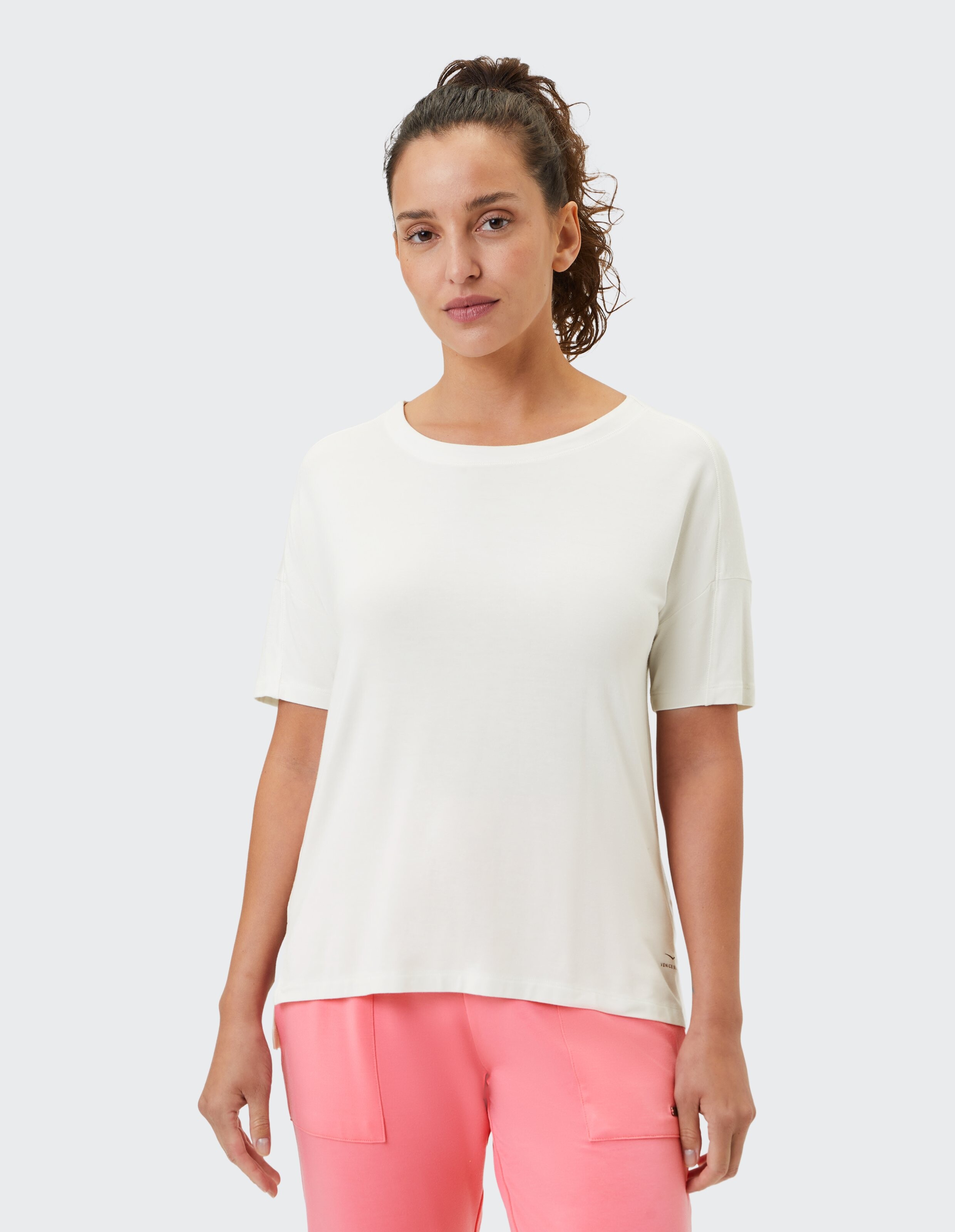 Lässiges weißes T-Shirt gepaart mit rosa Lounge-Hosen, perfekt für entspanntes Tragen.
