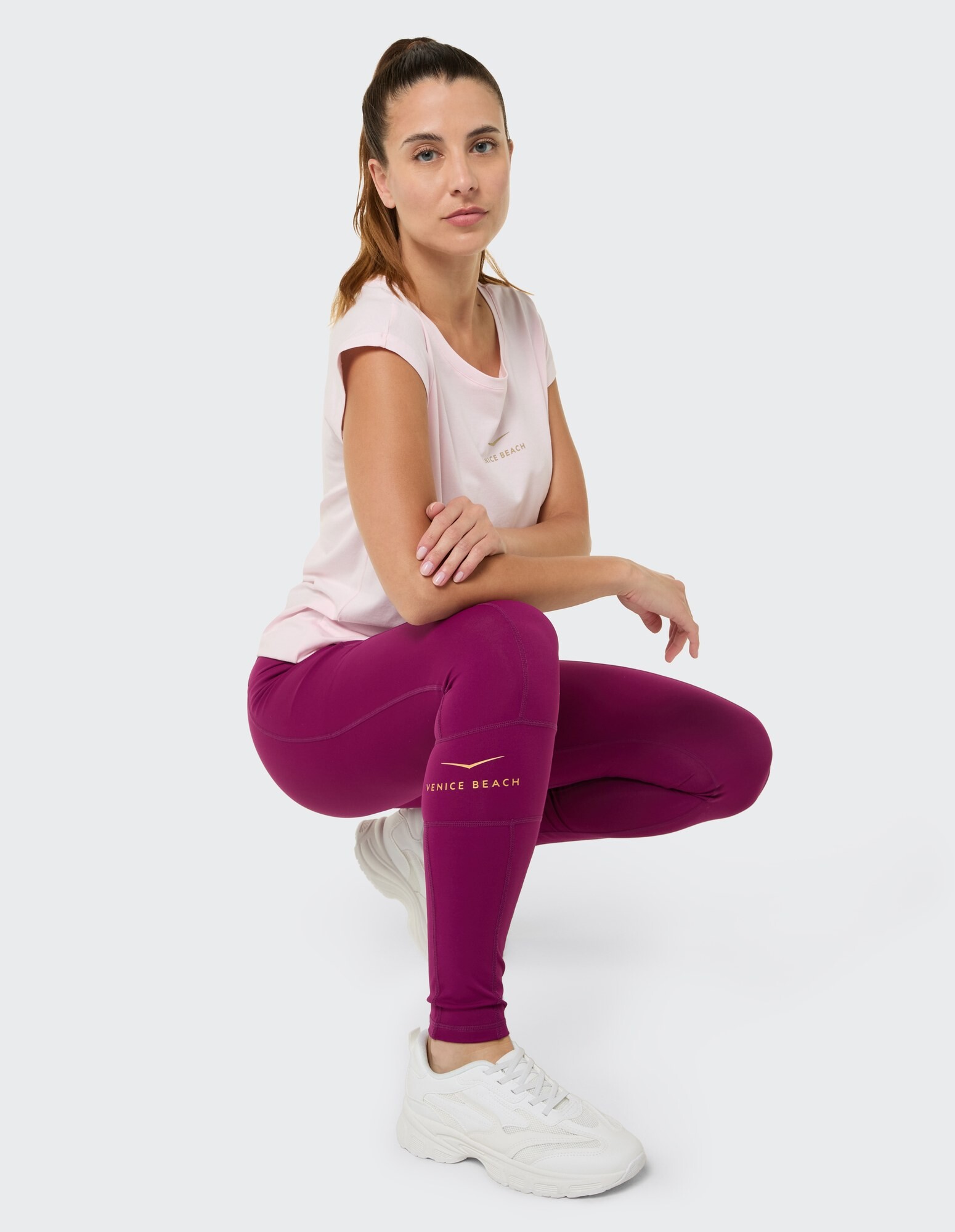 Frau in rosa T-Shirt und lila Leggings, gestylt für lässigen Komfort.