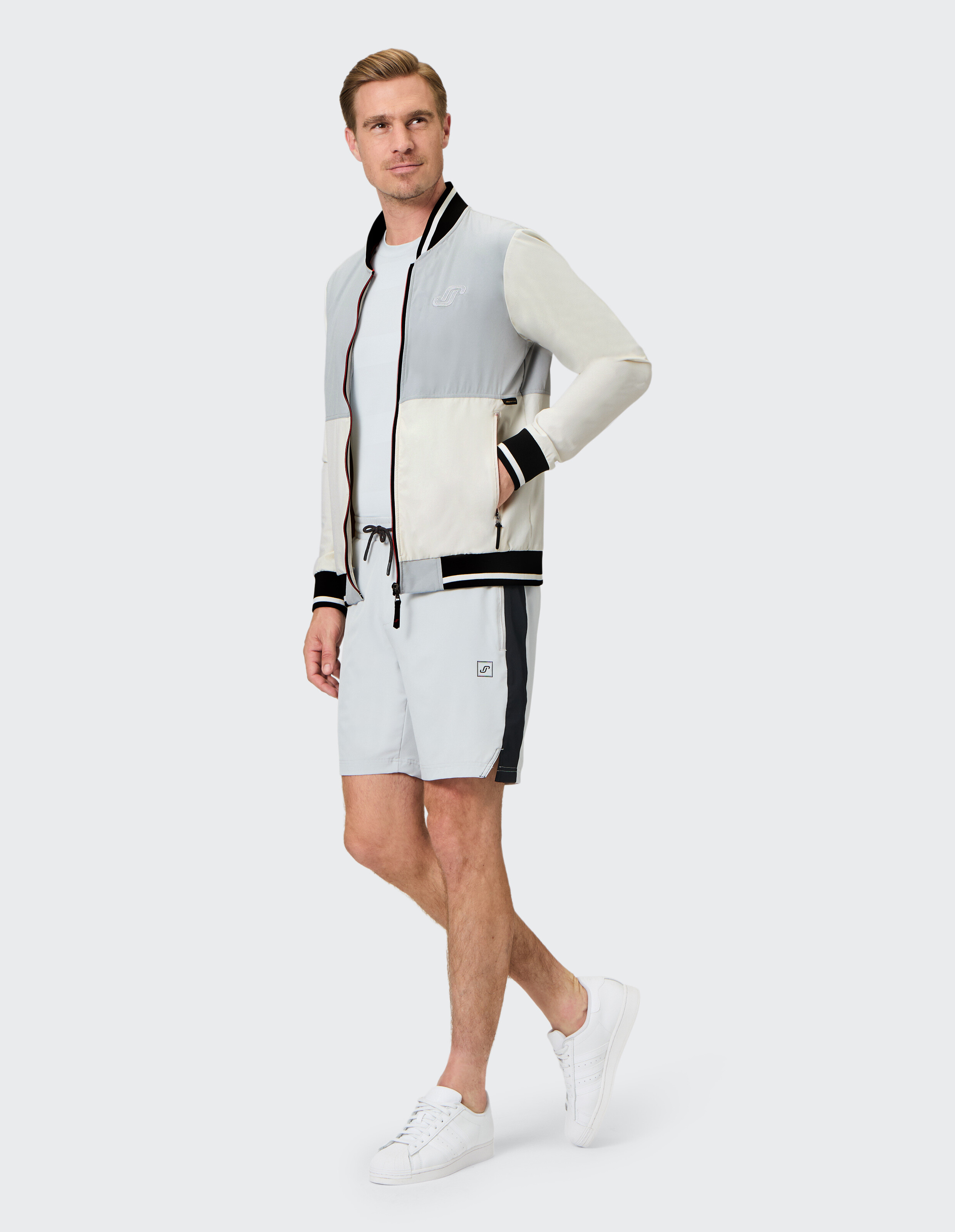 Mann trägt eine Farbblock-Bomberjacke und lässige Shorts für einen stilvollen Lounge-Look.