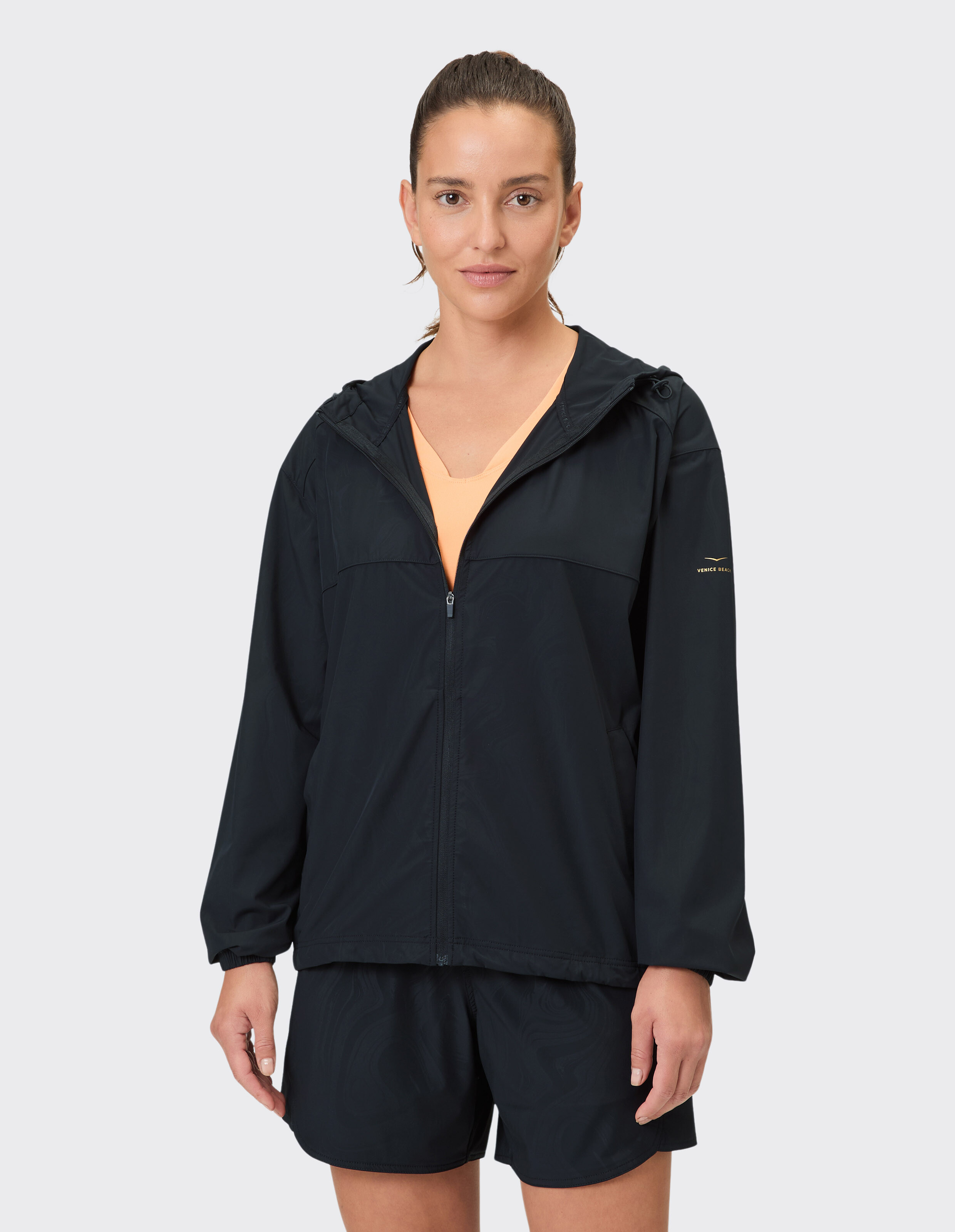 Frau trägt eine schwarze Windjacke mit Kapuze und Reißverschluss für lässige Outdoor-Aktivitäten.
