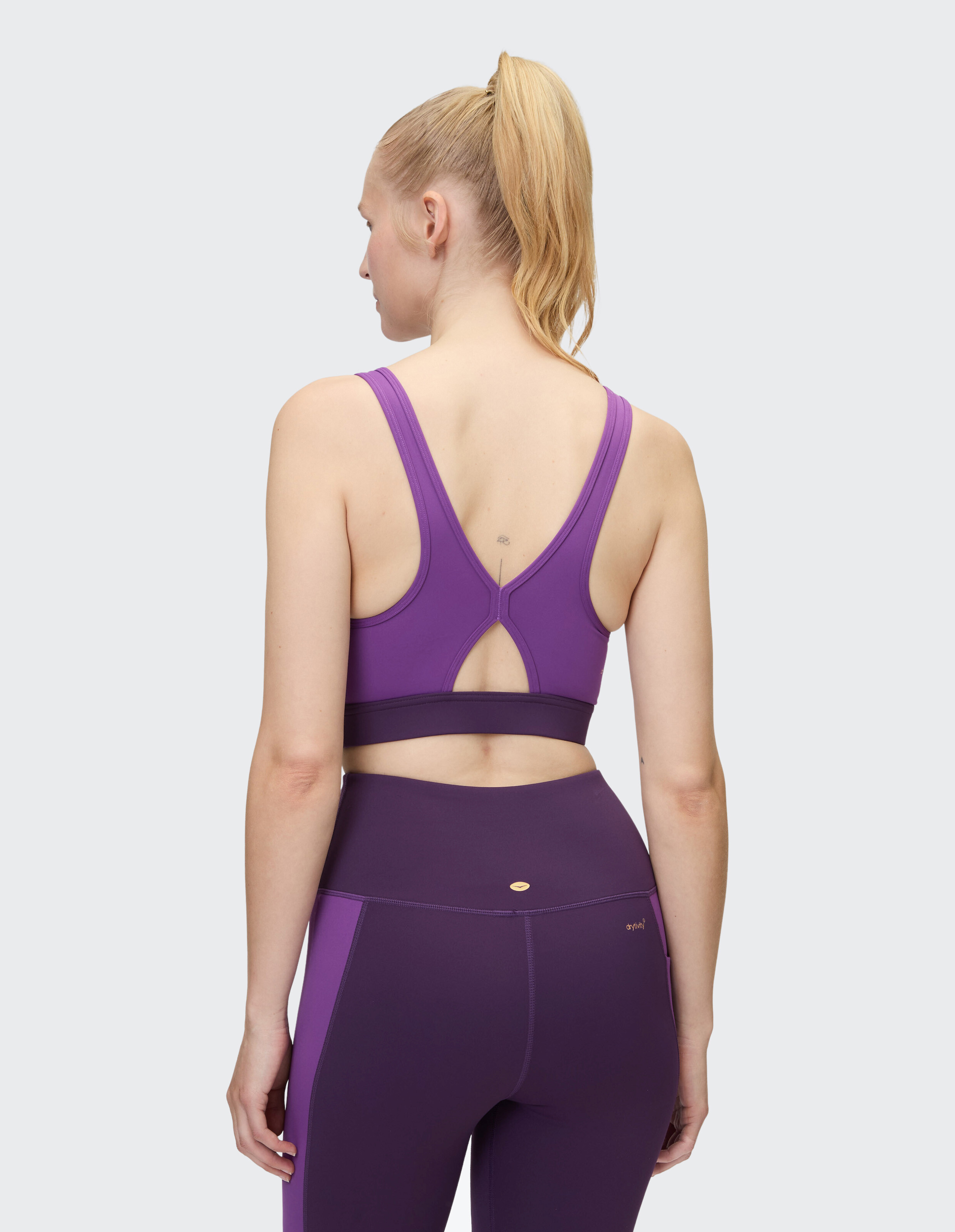 Rückansicht einer Frau in einem lila Sport-BH und passenden Leggings.