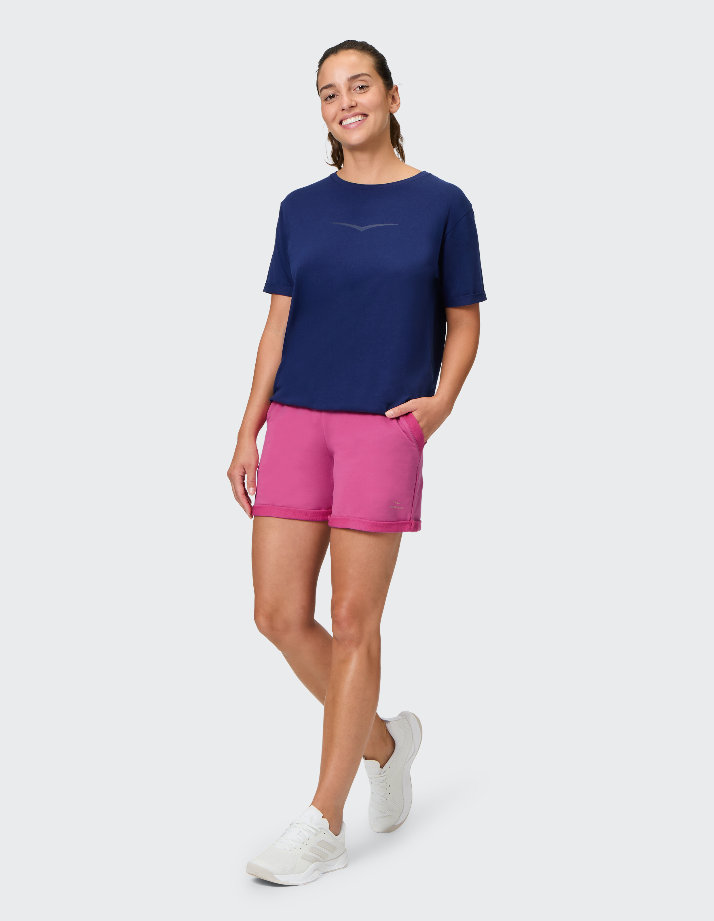 Frau in dunkelblauem T-Shirt und rosa Shorts, perfekt für Freizeitausflüge oder zum Faulenzen.