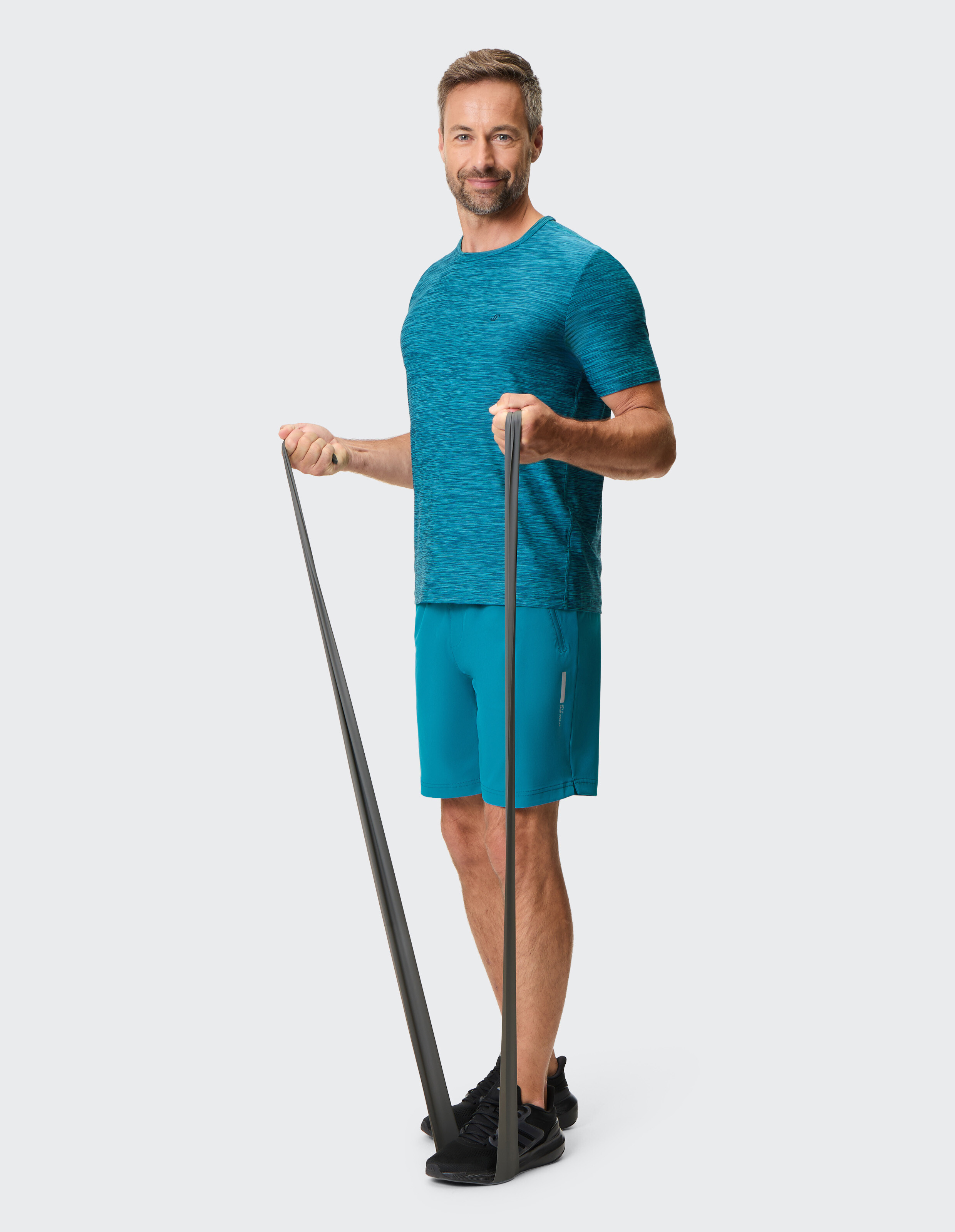 Mann in einem blau melierten T-Shirt und Shorts trainiert mit einem Widerstandsband.