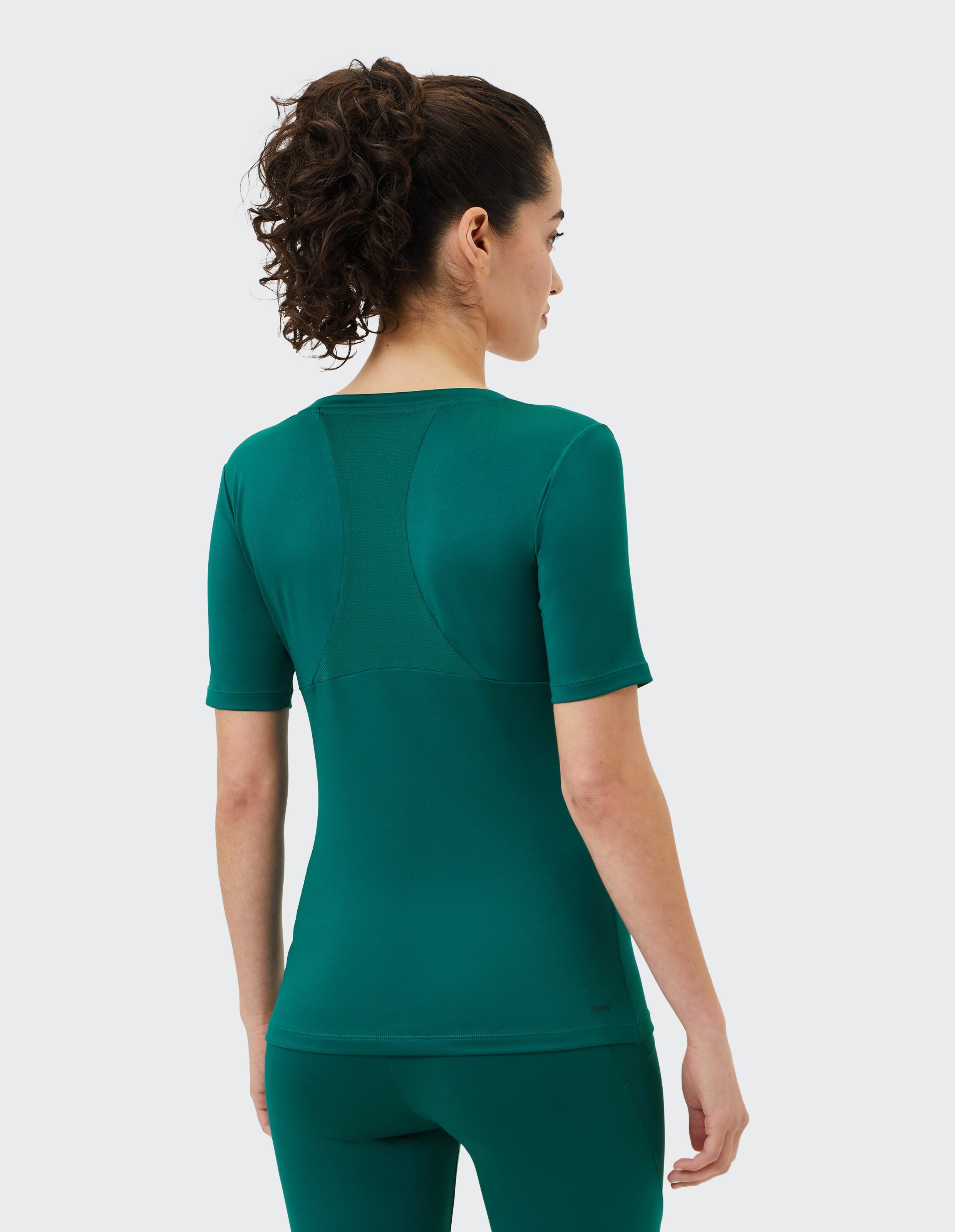 Frau trägt ein dunkelgrünes, kurzärmliges Sportshirt mit Mesh-Detail am Rücken.