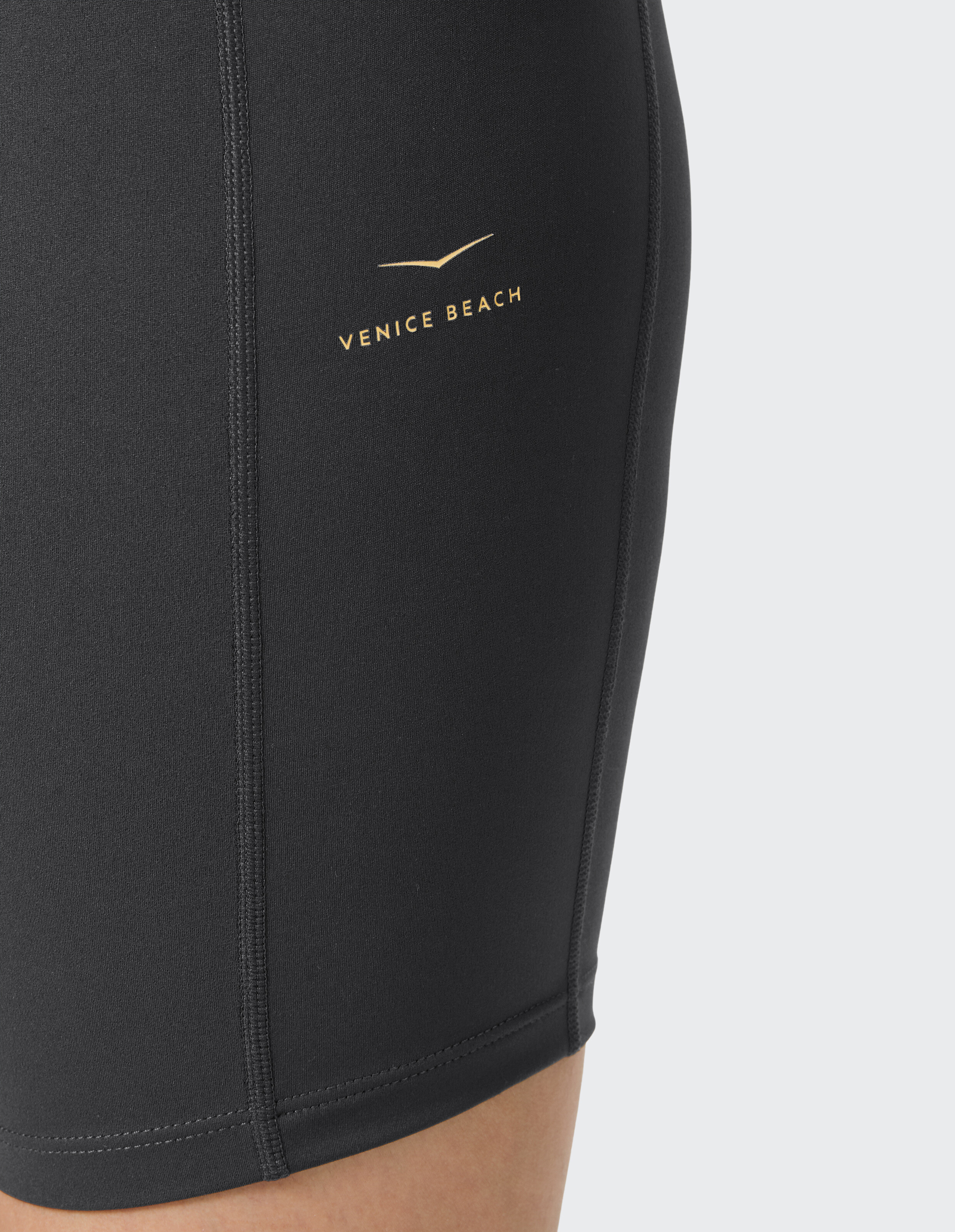Nahaufnahme einer schwarzen Venice Beach-Shorts mit goldenem Logo, ideal für Freizeitkleidung.