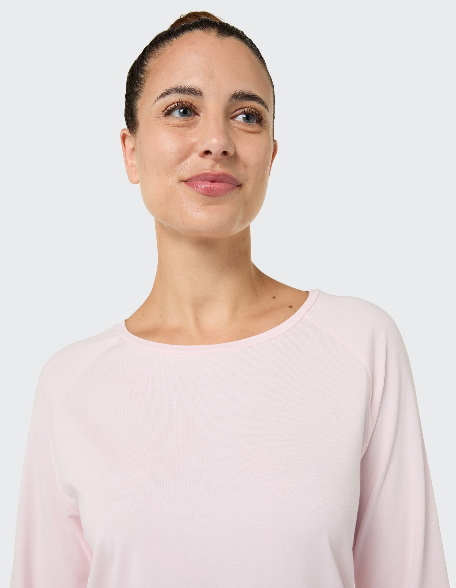 Nahaufnahme einer Frau in einem hellrosa Langarmshirt, das einen lässigen Stil unterstreicht.