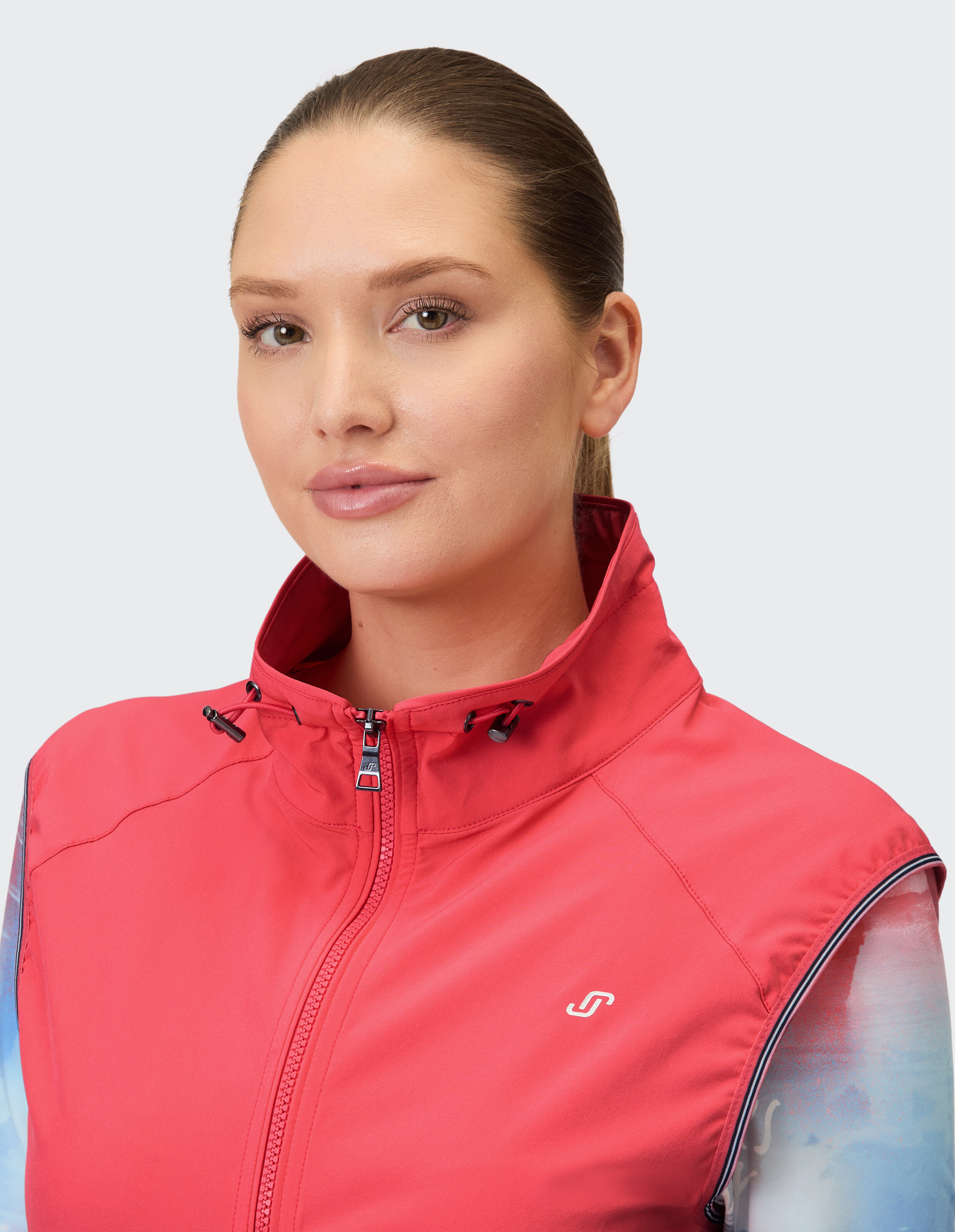 Nahaufnahme einer Frau, die eine stilvolle rote ärmellose Jacke mit Reißverschlusskragen trägt.