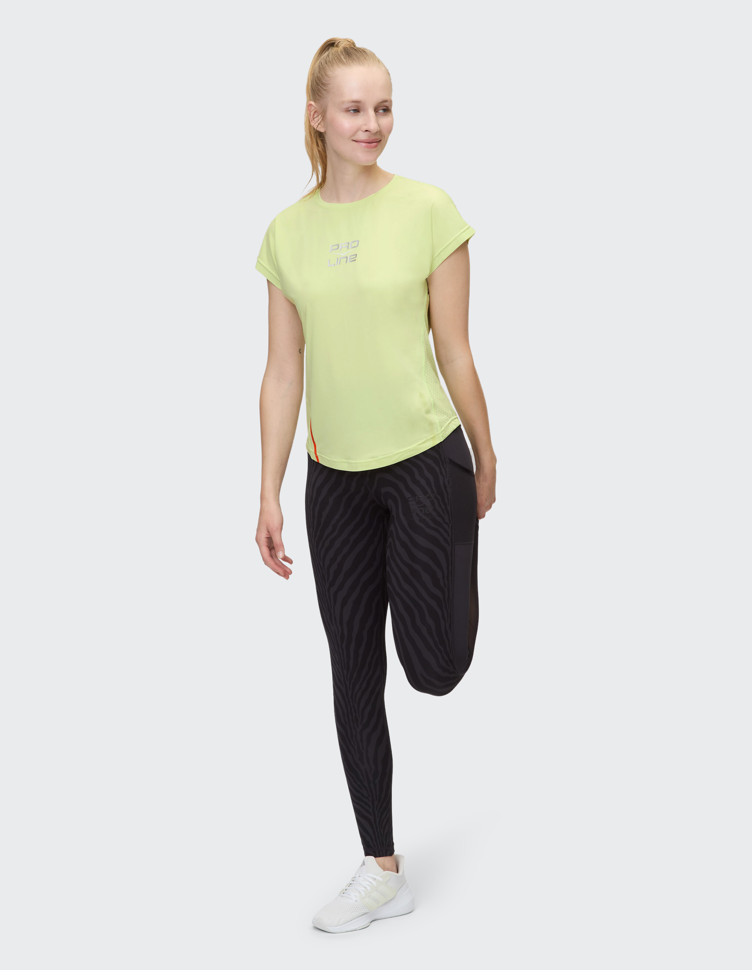Frau trägt ein lindgrünes Venice Beach Kurzarmshirt Berkeley und gemusterte Leggings.
