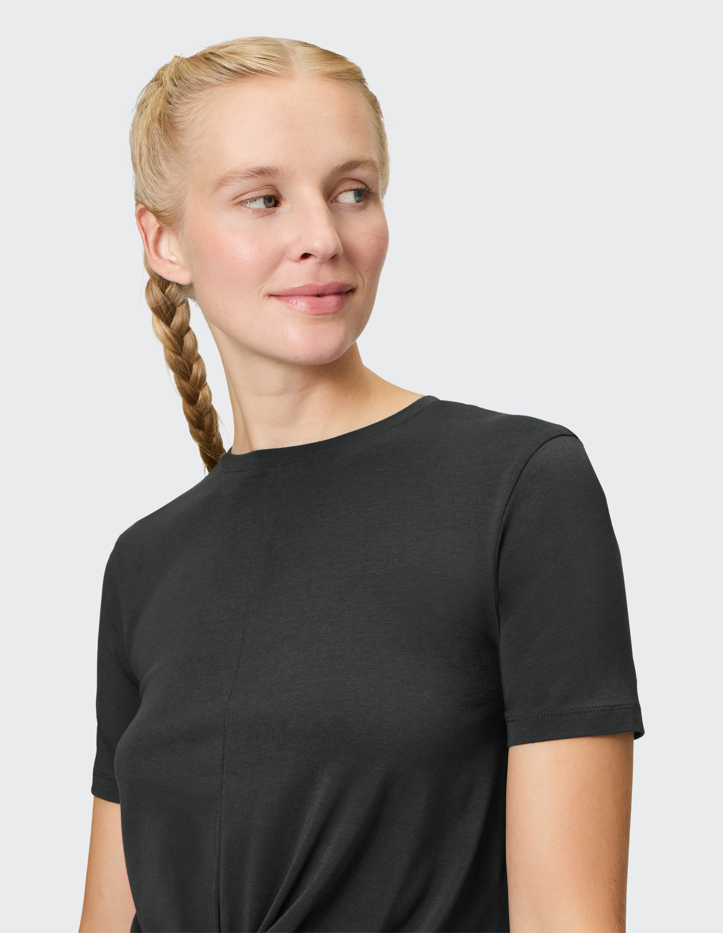 Frau trägt ein gemütliches schwarzes Kurzarm-Freizeit-T-Shirt vor hellem Hintergrund.