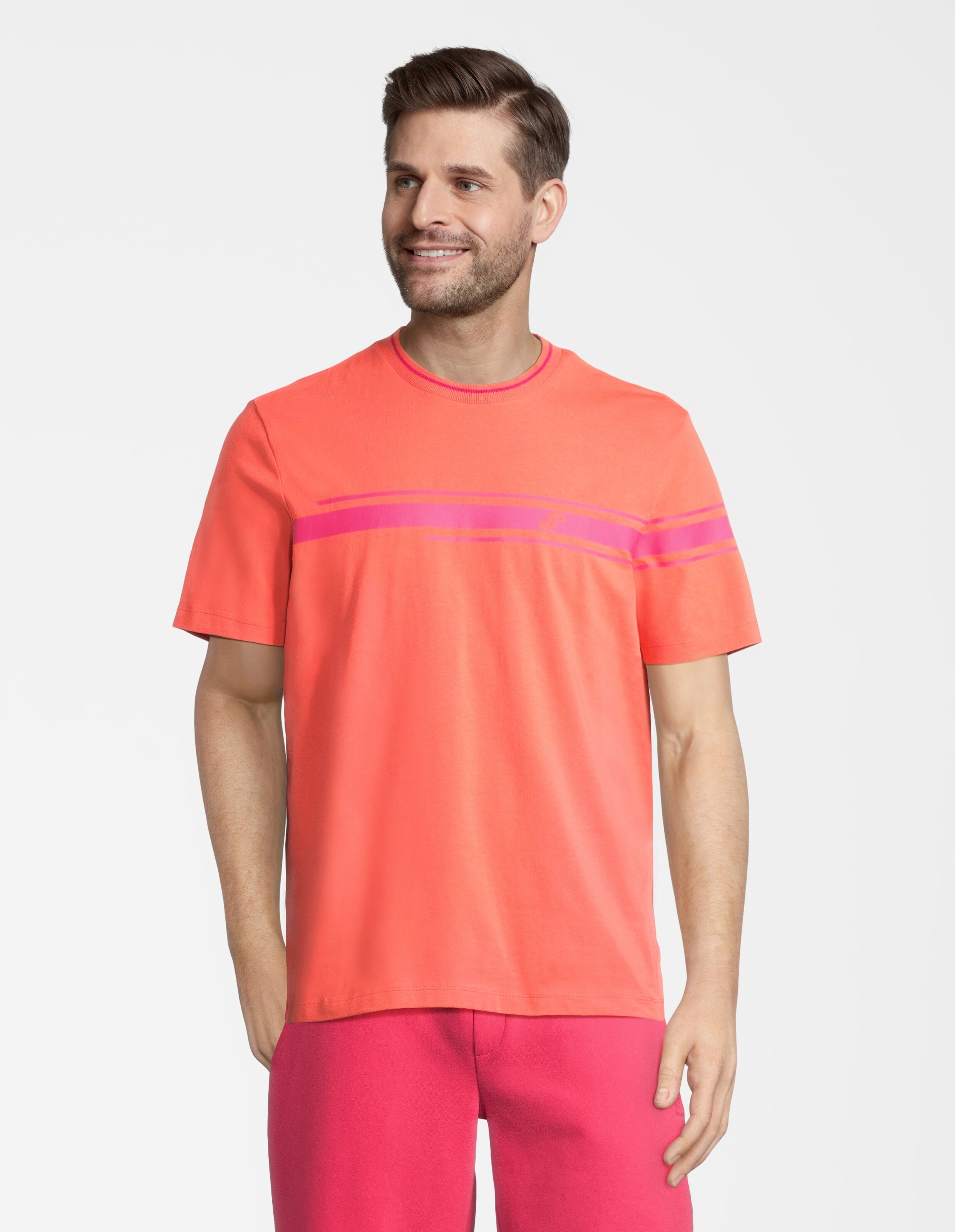 Mann trägt ein korallfarbenes Freizeit-T-Shirt mit rosa Streifen für einen bequemen Lounge-Look.