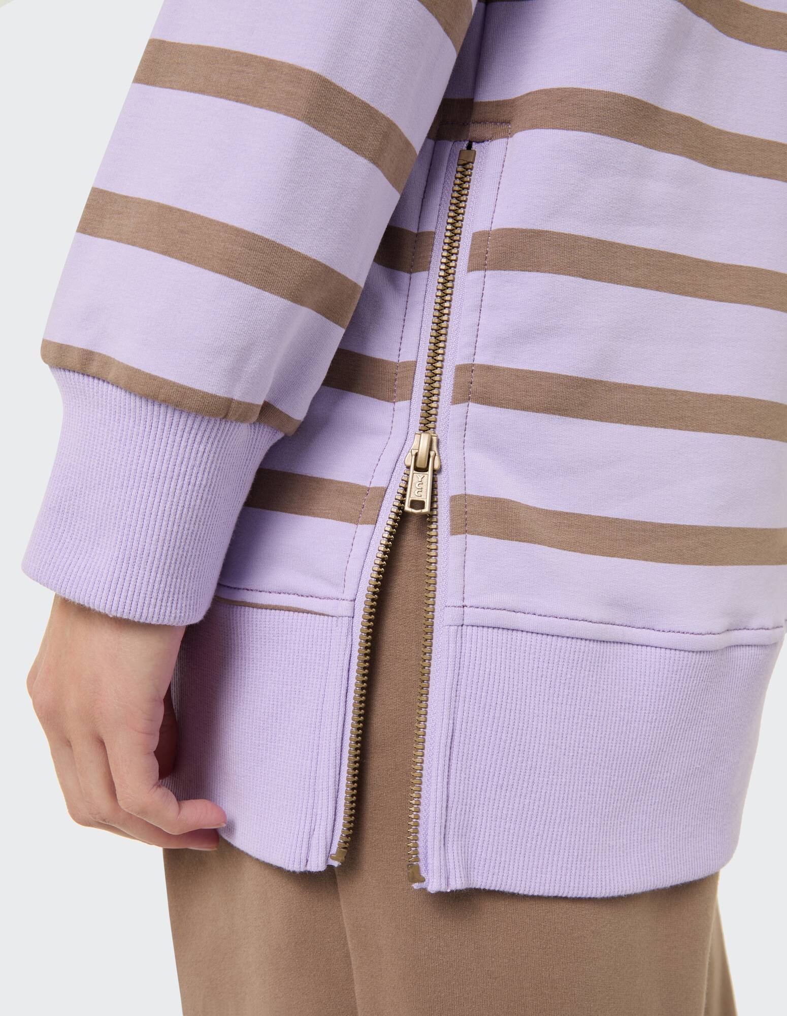 Nahaufnahme eines lila gestreiften Sweatshirts mit Reißverschlussdetail und gerippten Bündchen.